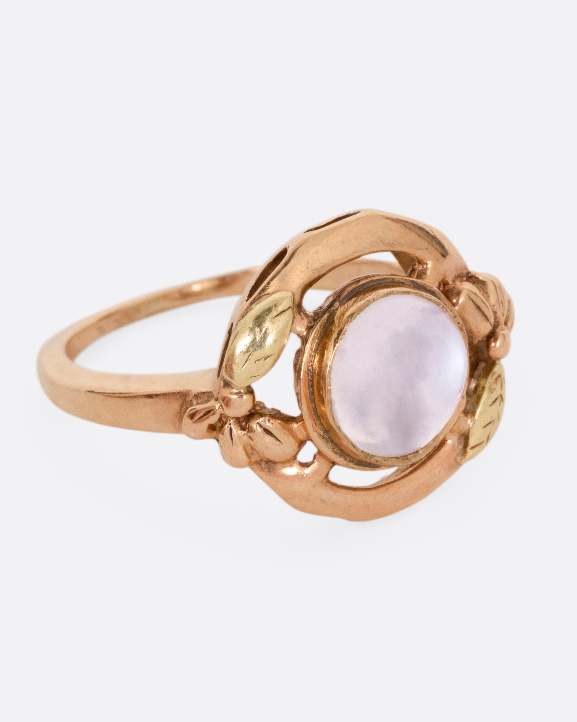 A rose and yellow gold moonstone cabachon ring, shown from the side.