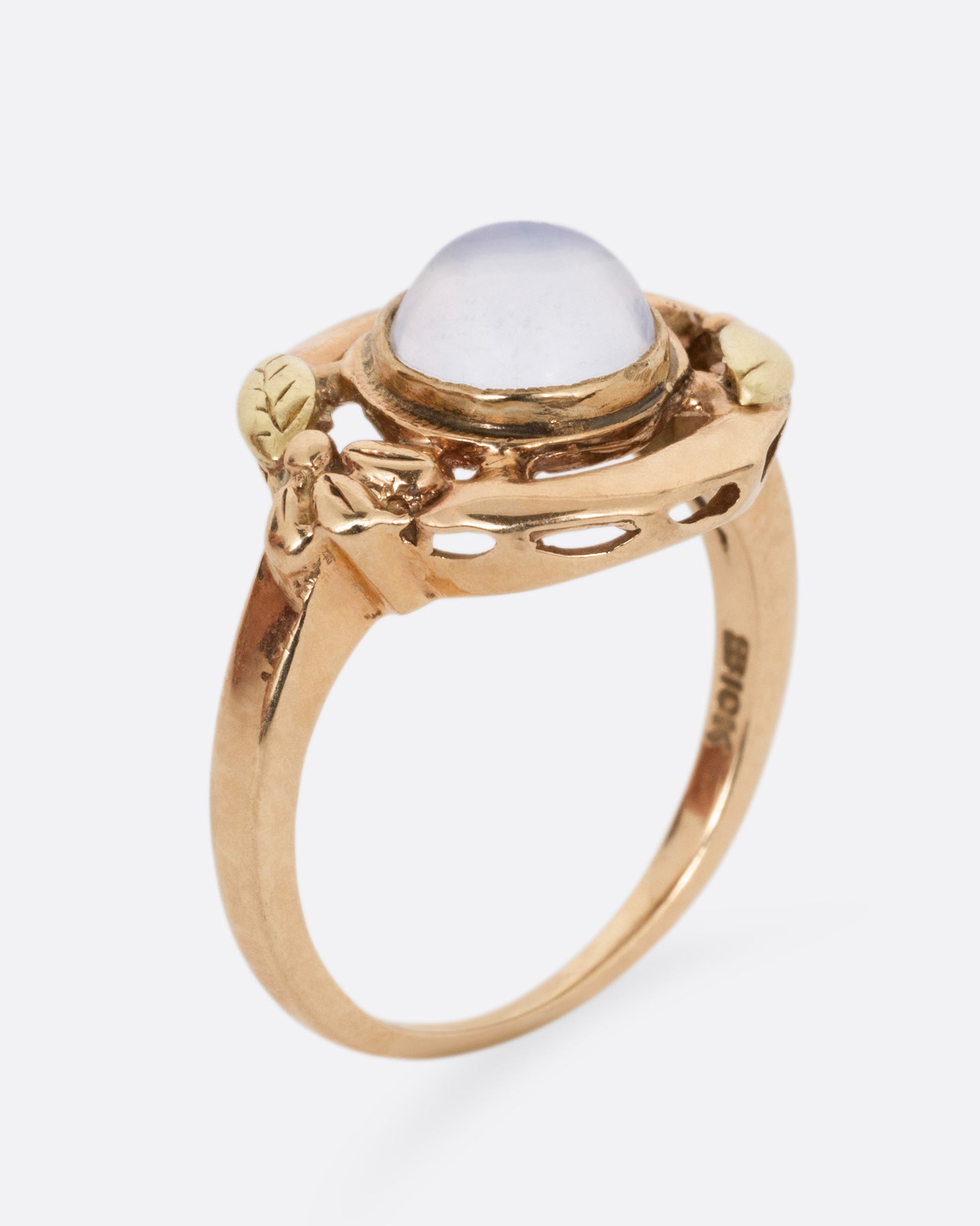 A rose and yellow gold moonstone cabachon ring, shown from the side standing up.