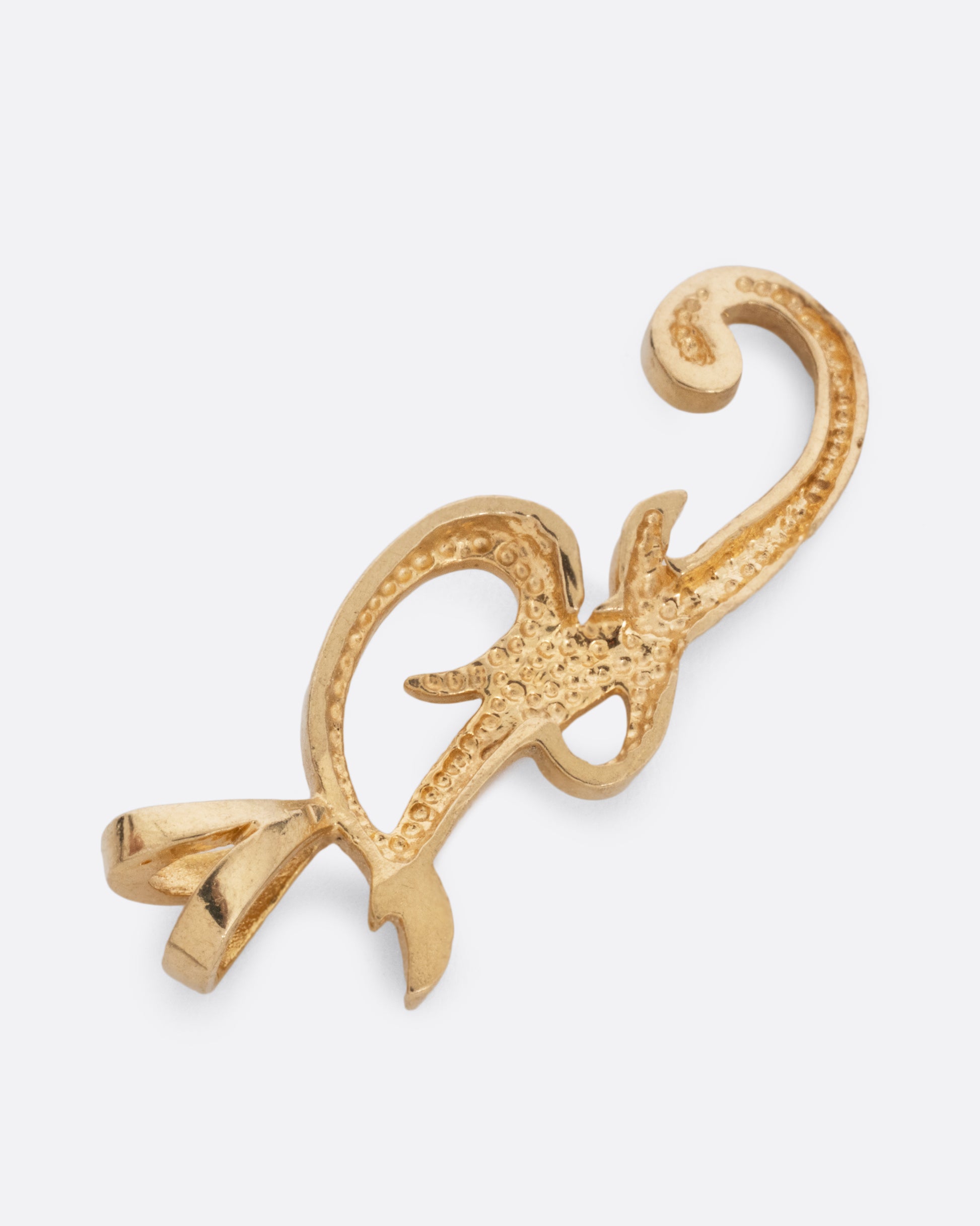 A yellow gold cursive 'F' pendant, shown from the back.