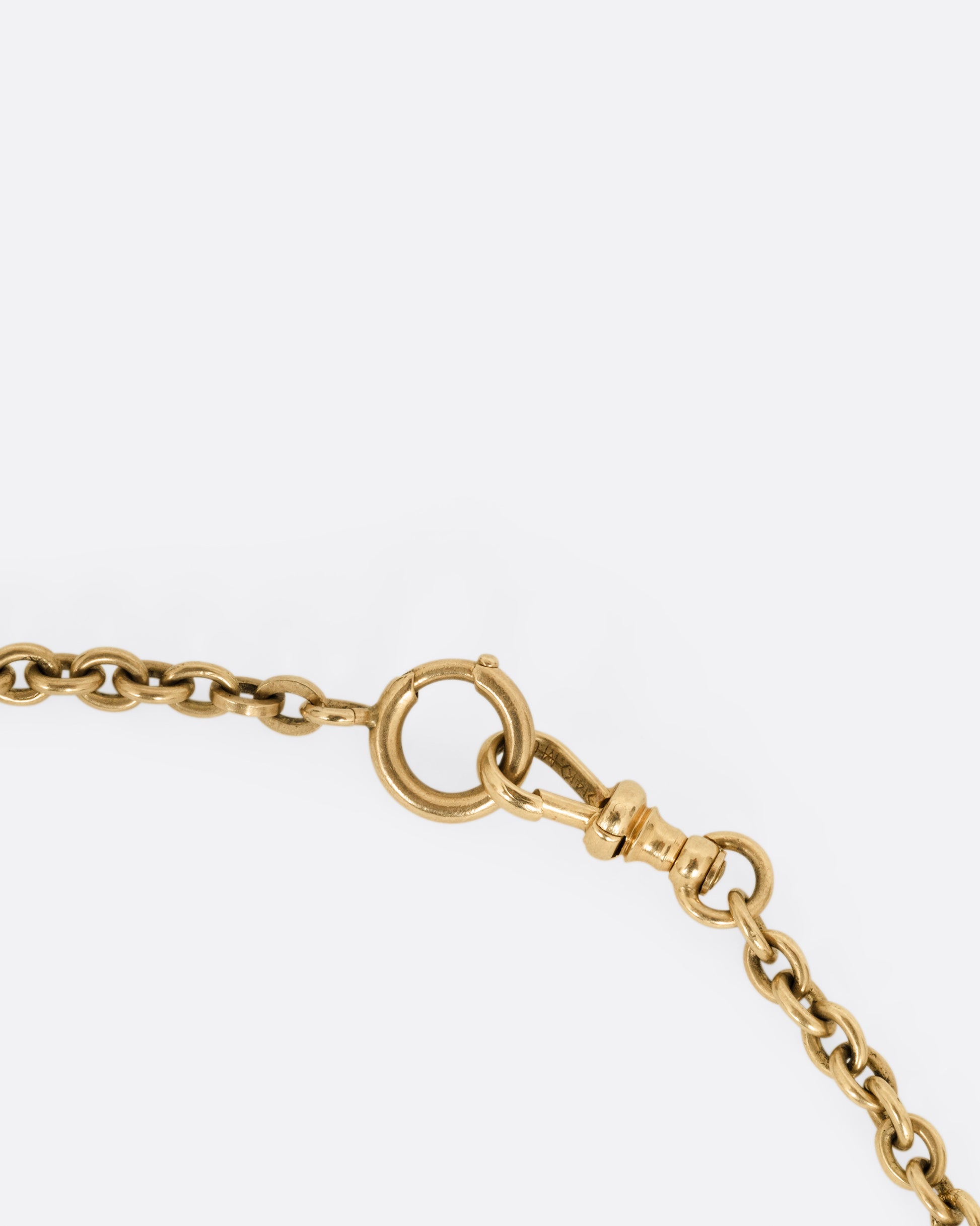 A close up of the clasp of a yellow gold curb chain necklace.