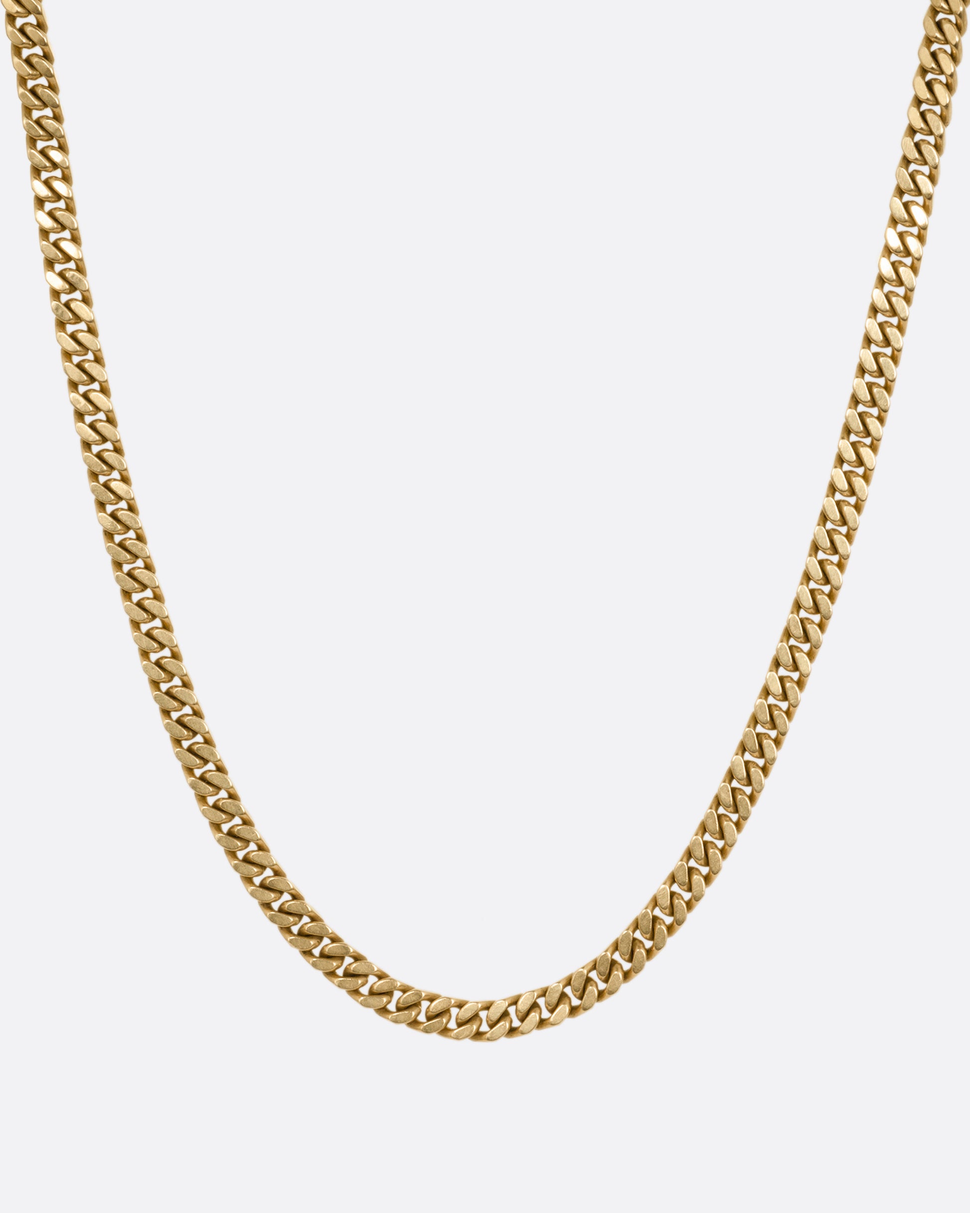 A yellow gold curb chain necklace, shown from the front.