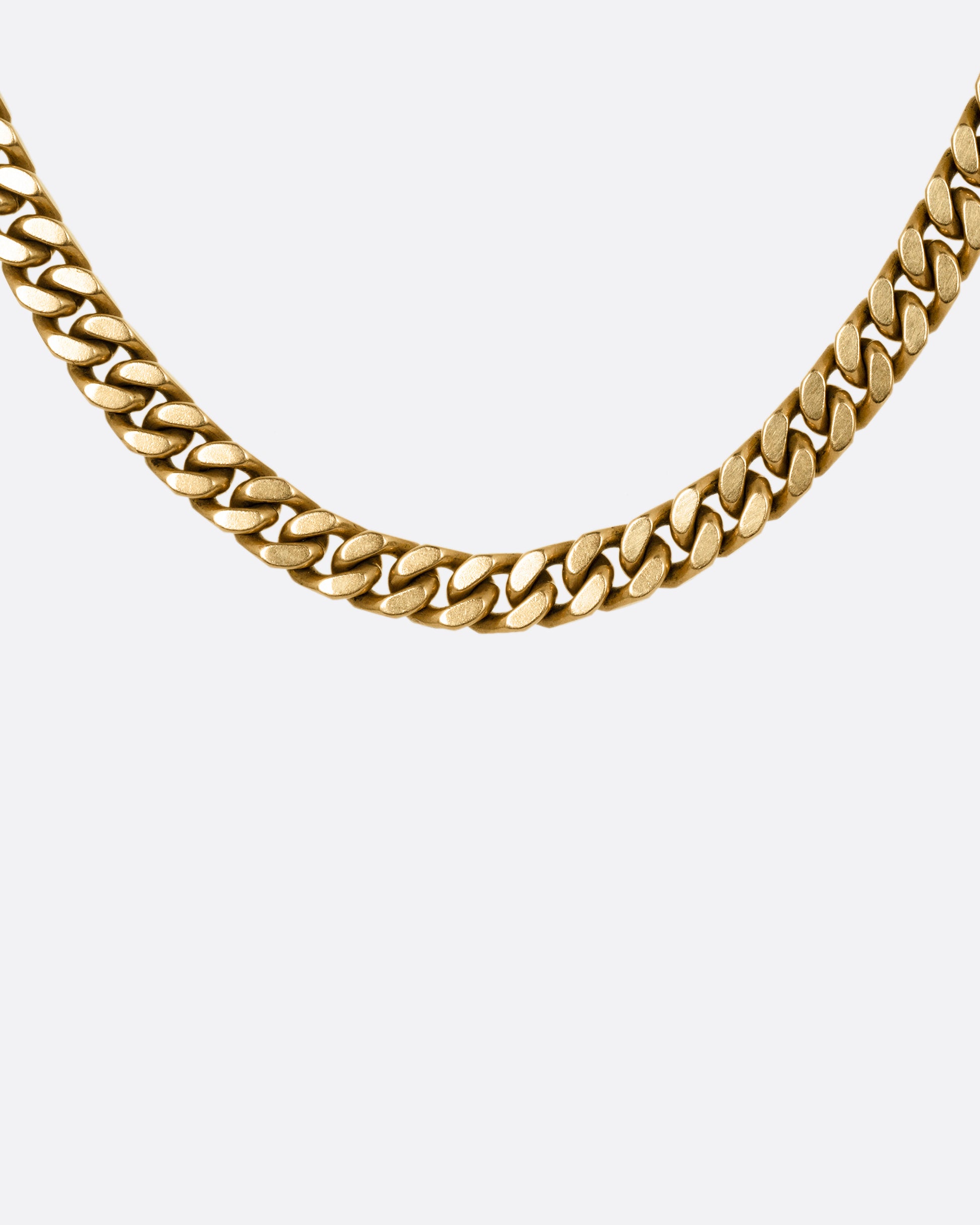A yellow gold curb chain necklace, shown from the front.