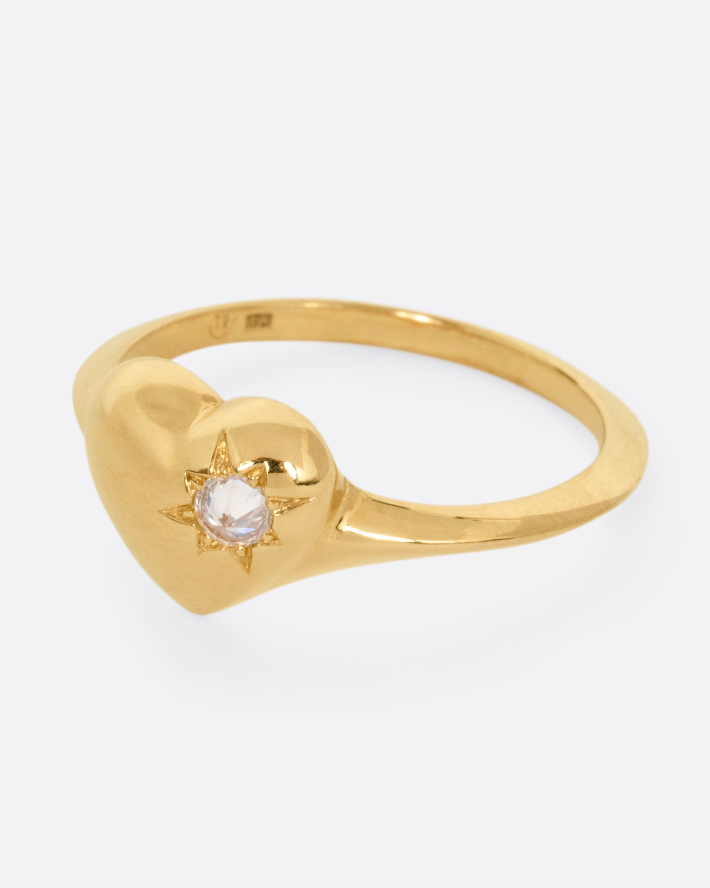 A yellow gold heart shaped ring with a reverse set diamond, shown from the side.