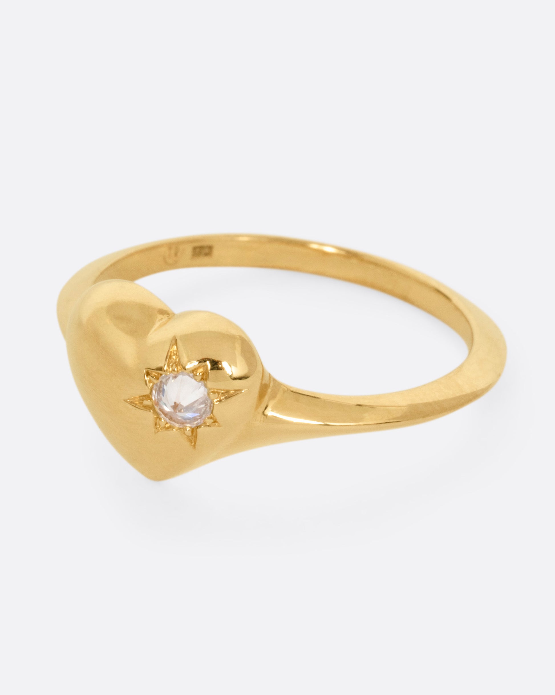 A yellow gold heart shaped ring with a reverse set diamond, shown from the side.