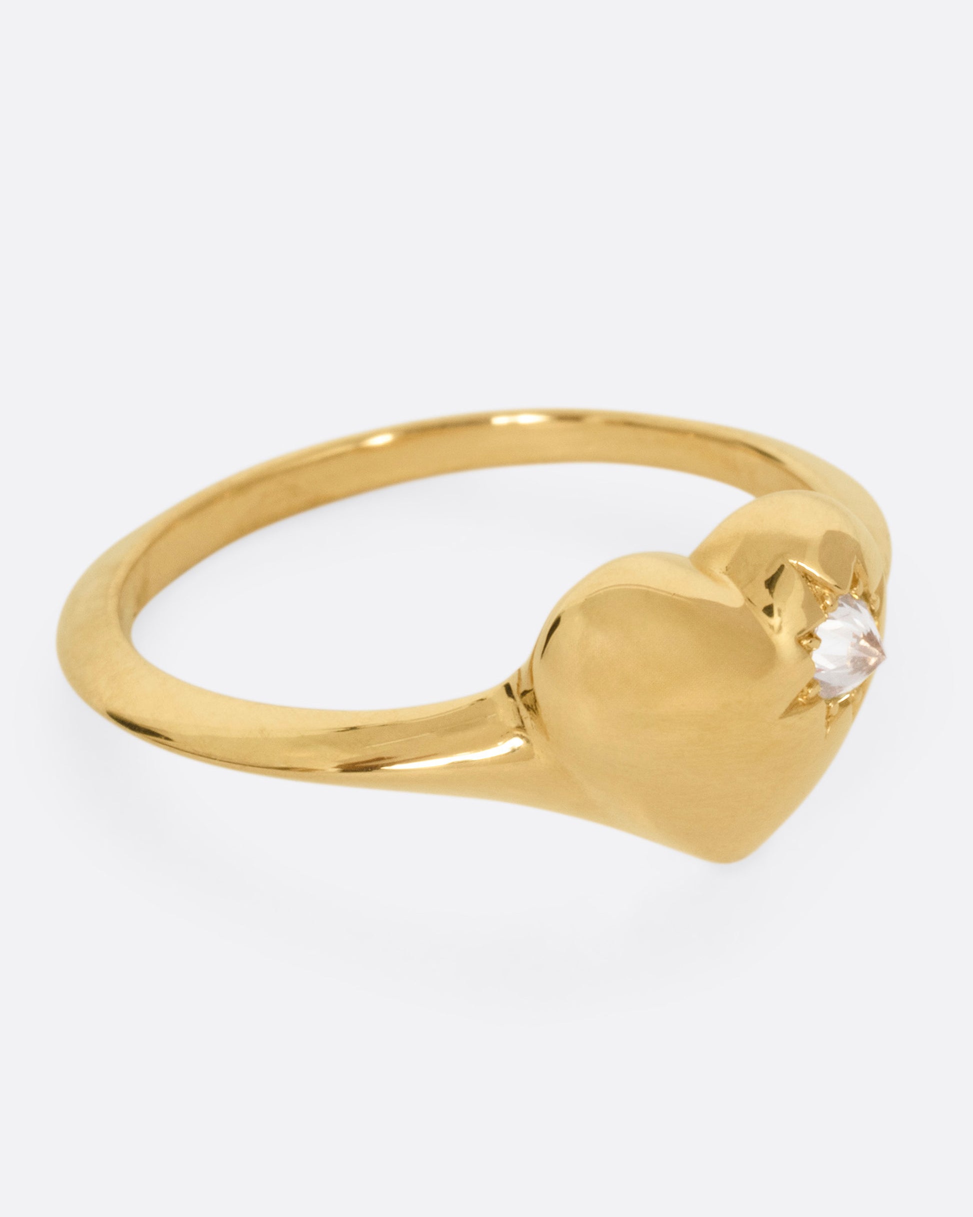 A yellow gold heart shaped ring with a reverse set diamond, shown from the side.