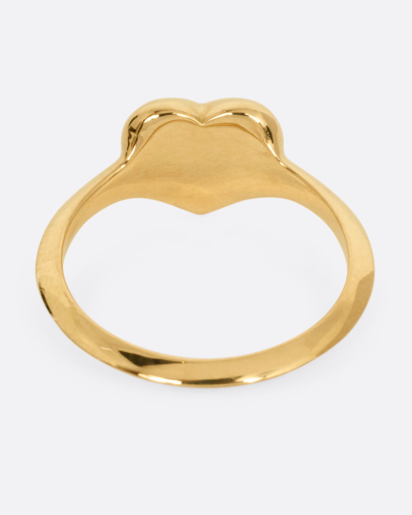 A yellow gold heart shaped ring with a reverse set diamond, shown from the back.