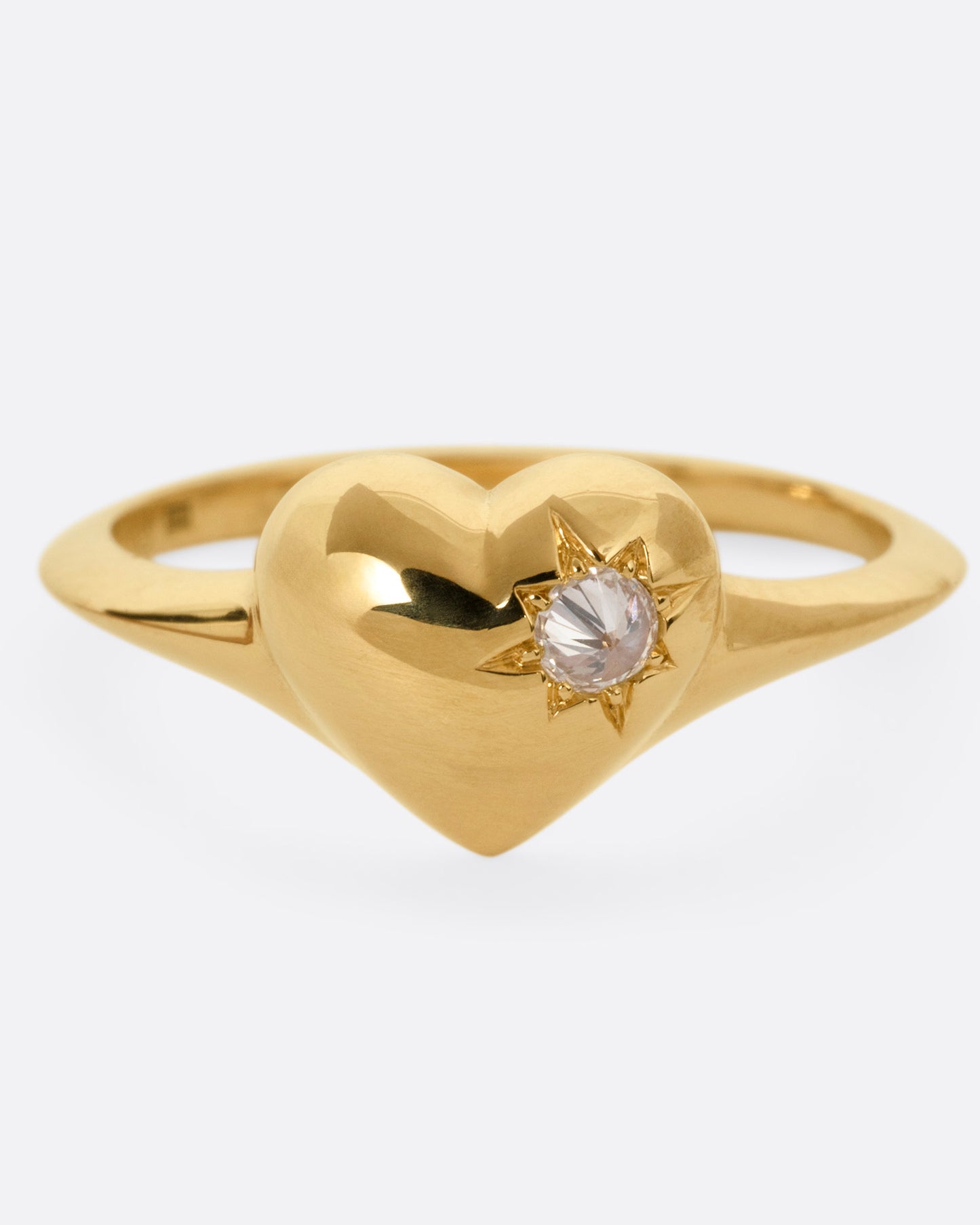 A yellow gold heart shaped ring with a reverse set diamond, shown from the front.