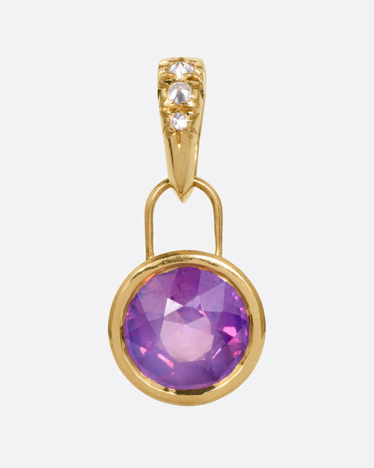 A yellow gold pendant with a pink sapphire and a diamond studded clip lock bail, shown from the front.