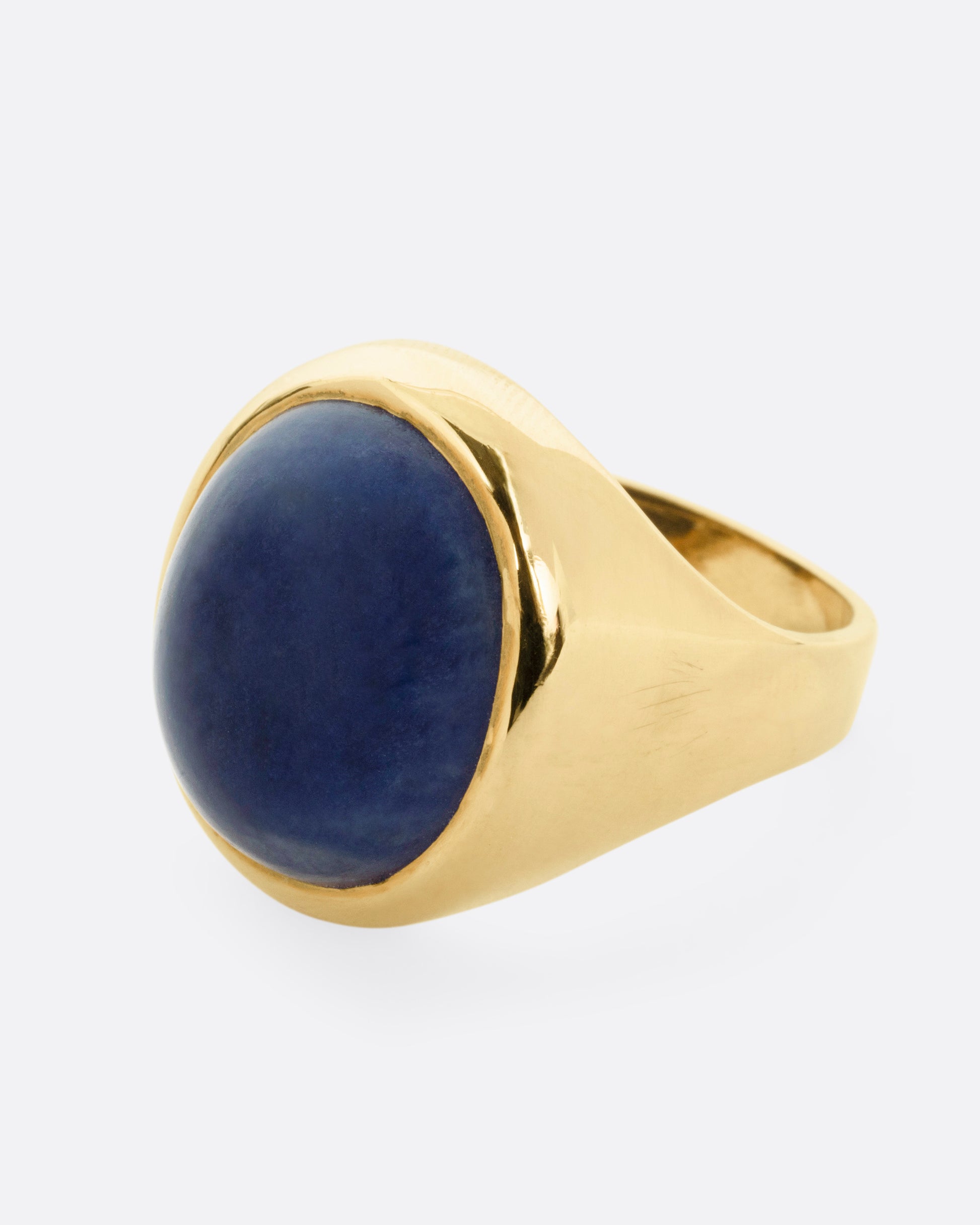 A yellow gold signet ring with a lapis cabochon, shown from the side.