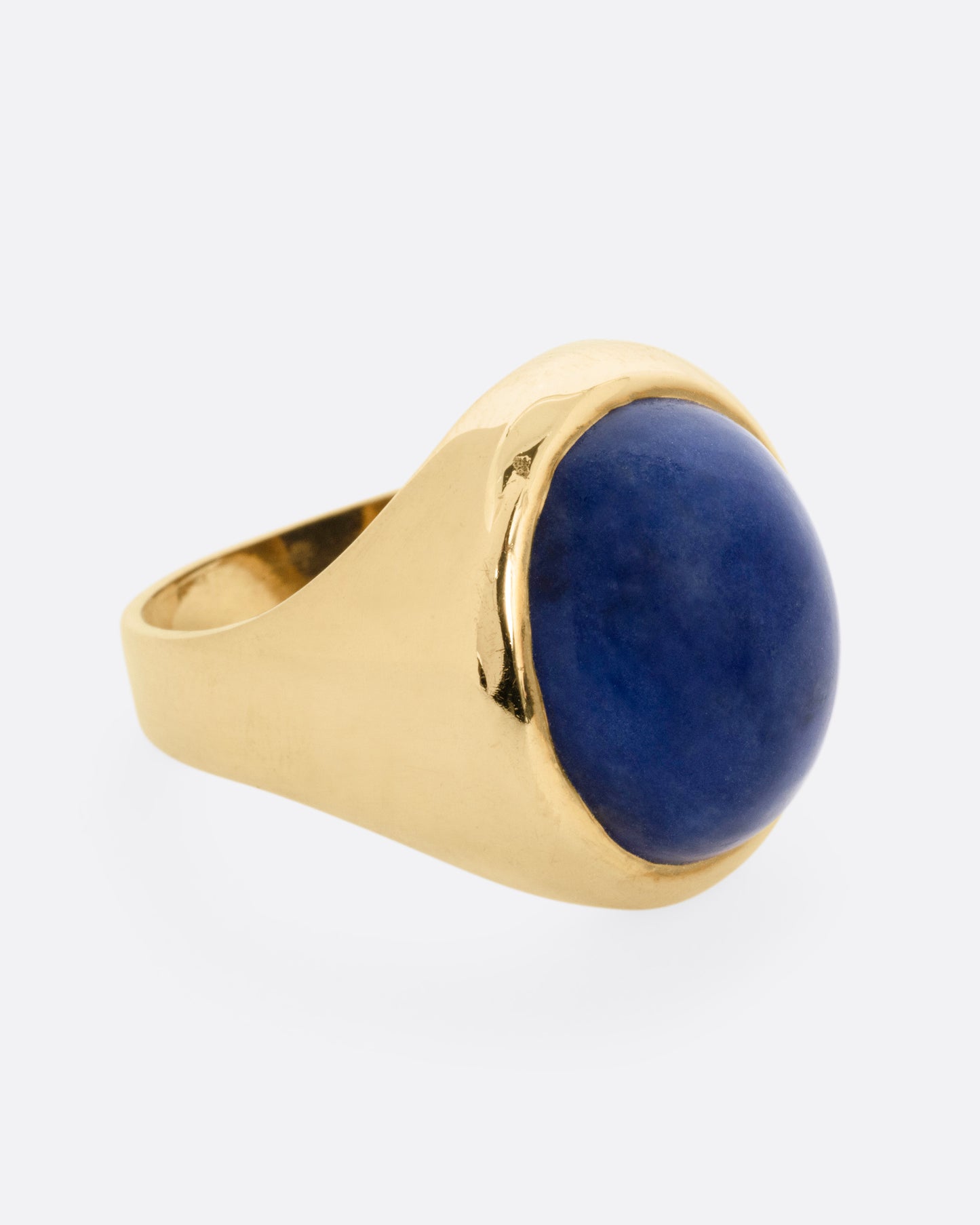 A yellow gold signet ring with a lapis cabochon, shown from the side.