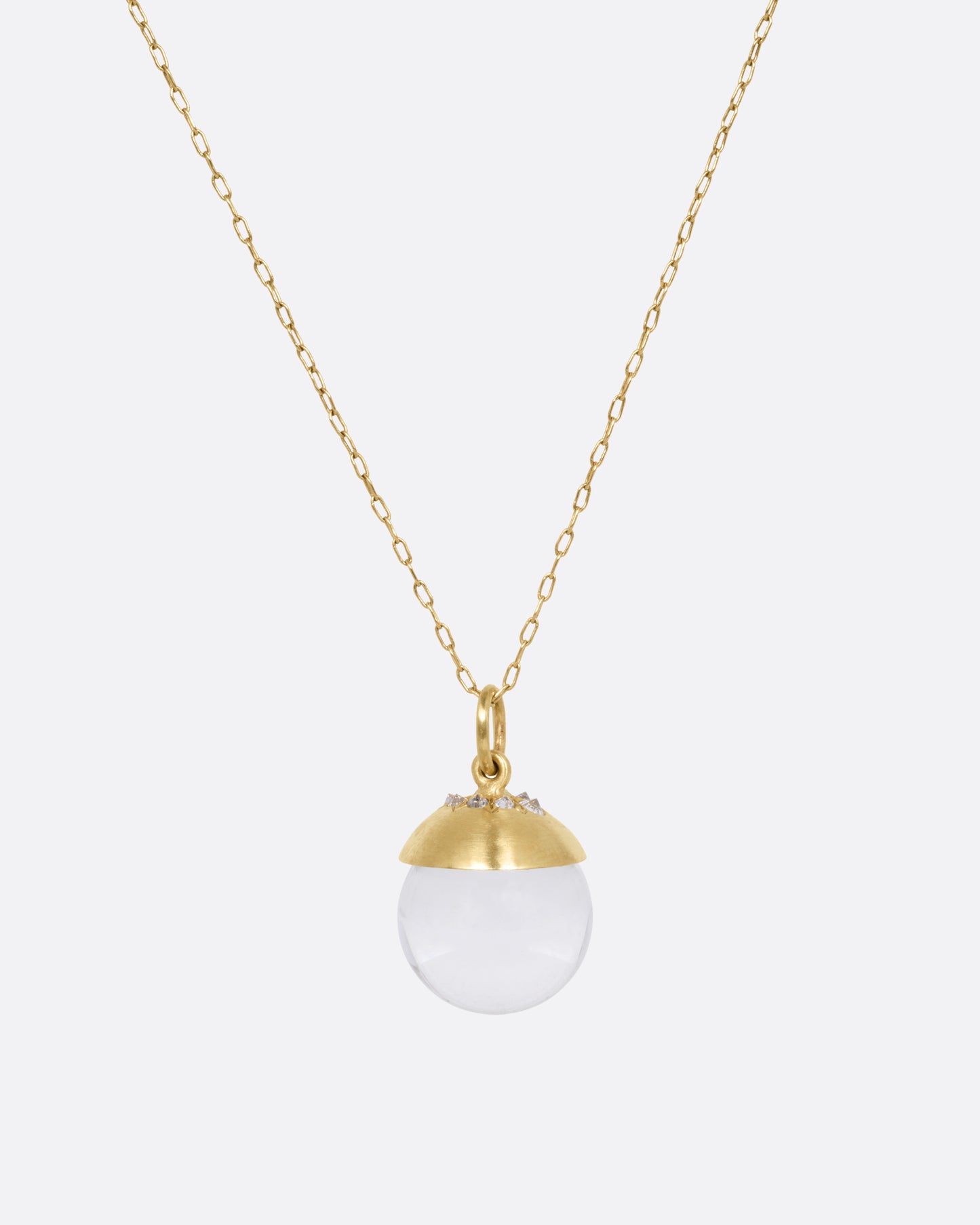 A yellow gold cable chain necklace with a quartz sphere pendant topped with gold and reverse set diamonds. Shown from the front.