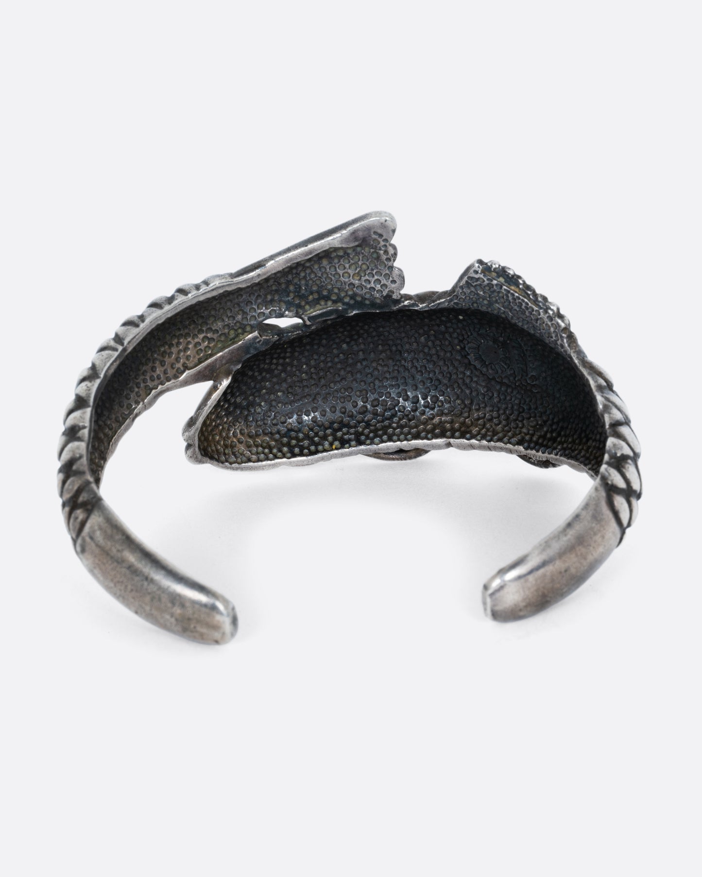 A silver fish shaped bracelet shown from the back.