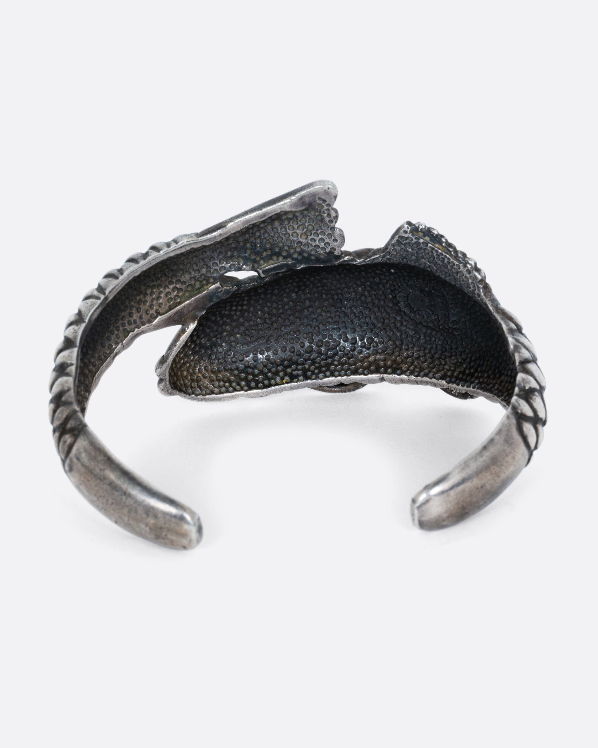 A silver fish shaped bracelet shown from the back.