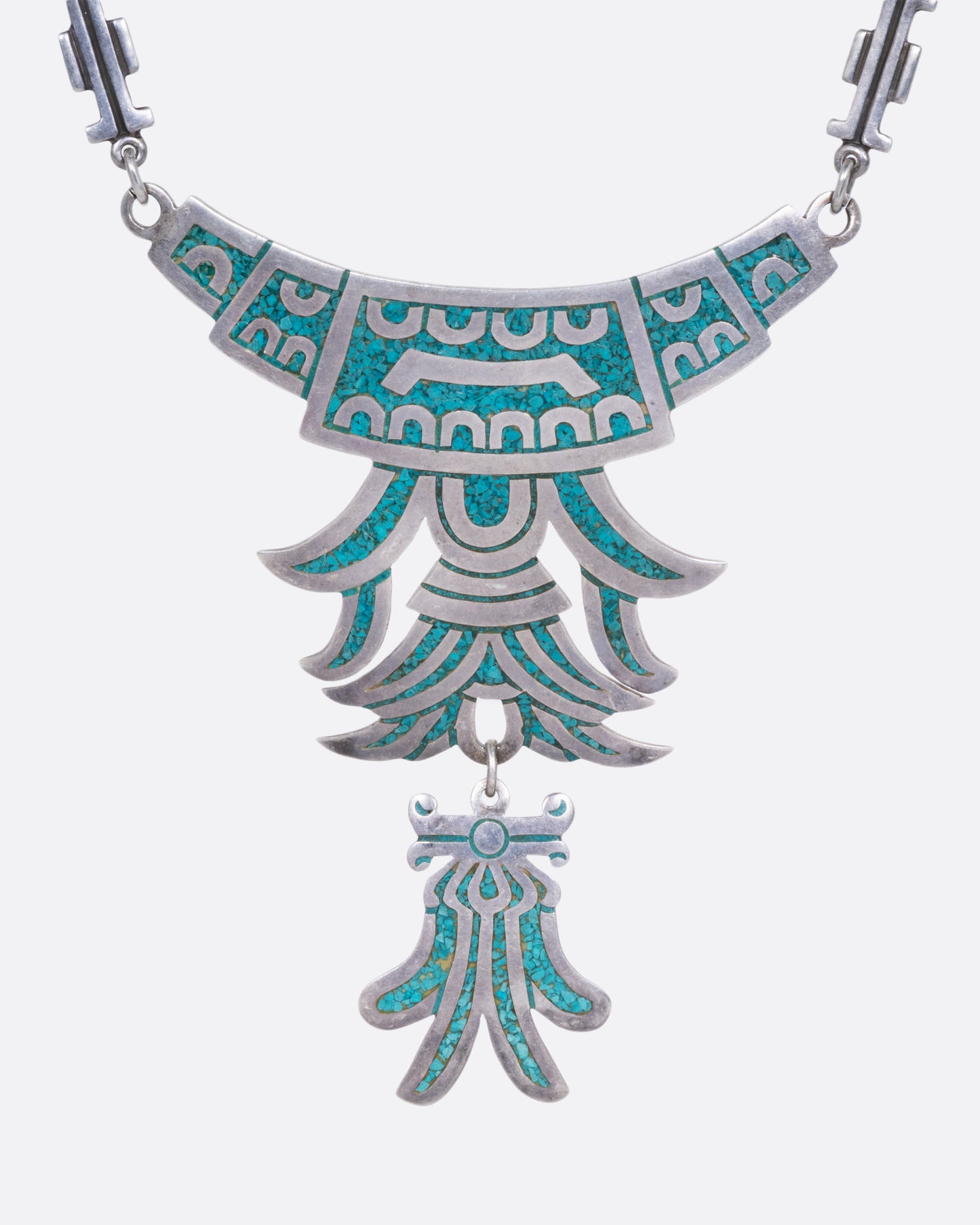 A silver necklace collar with turquoise chip inlay and a dangling bottom piece, shown from the front.