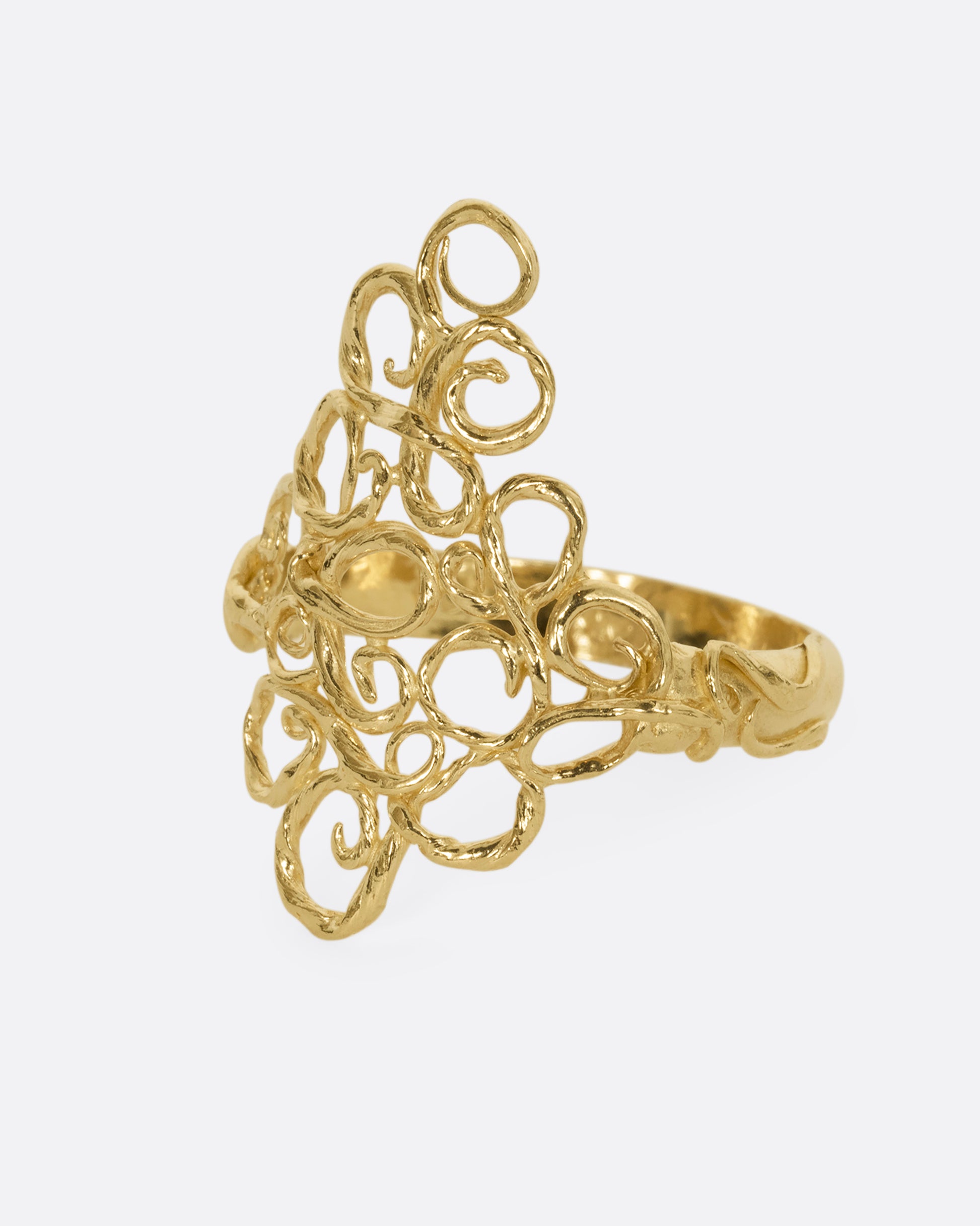 A yellow gold ring with filigree in the shape of a diamond at its center. Shown from the side.