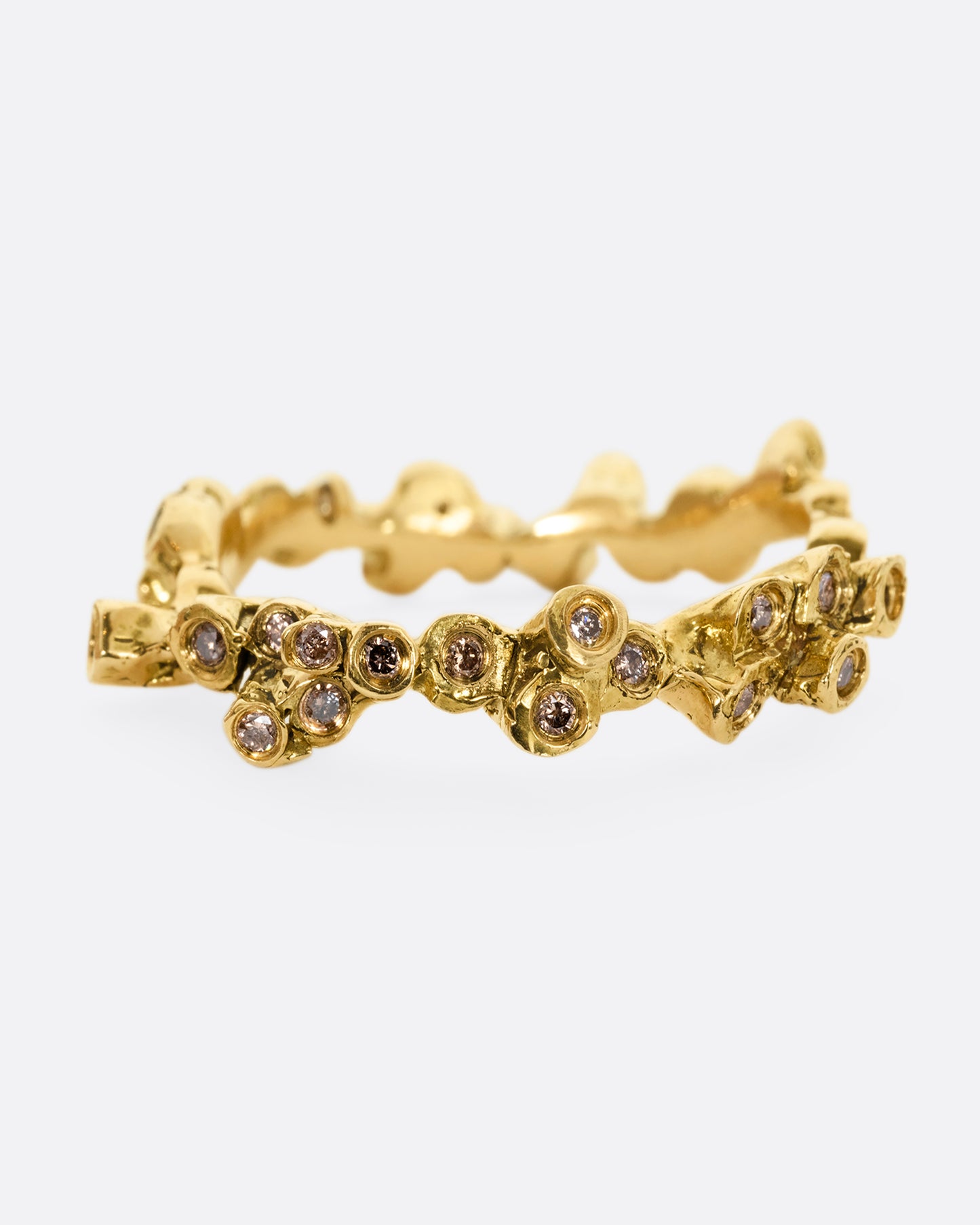 A yellow gold ring with cognac diamonds in protruding bezel settings that wrap around the entire band. Shown from the front.