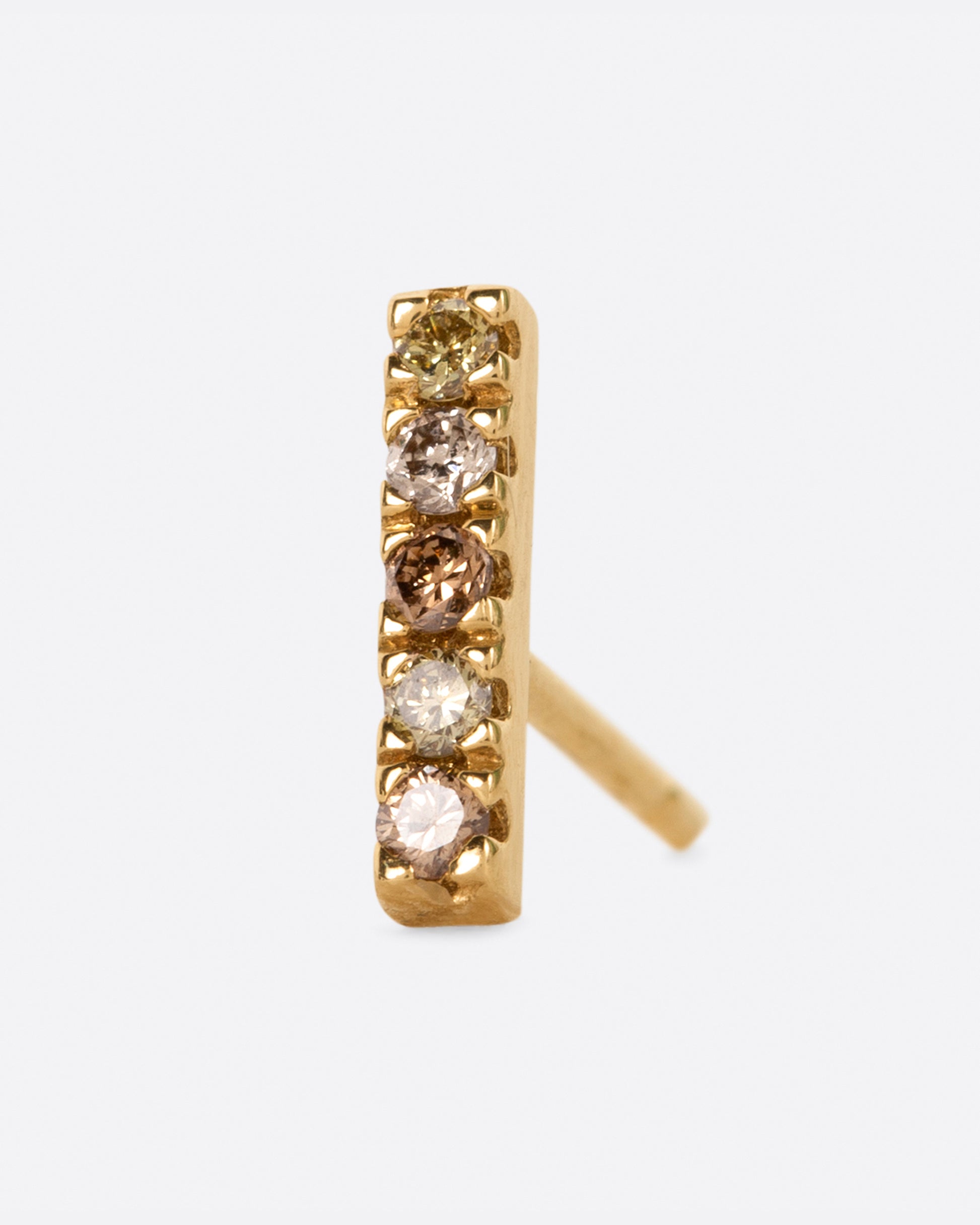 A yellow gold bar stud with a mix of five olive, dark and light champagne diamonds. Shown from the front.