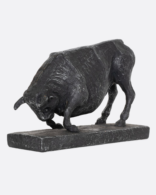 Bronze sculpture of a charging bull shown at an angle from the side.