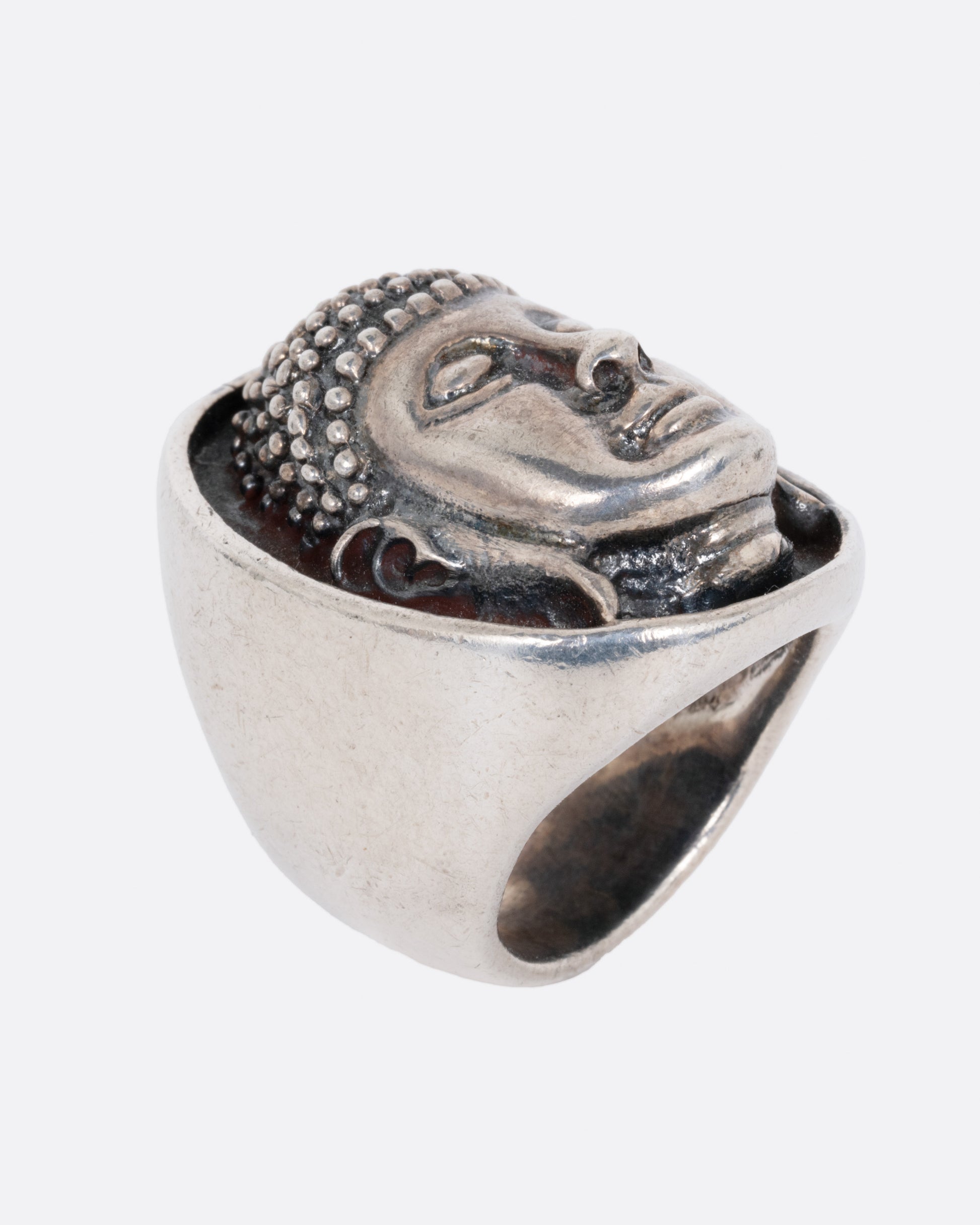 A silver ring with the Buddha's face. Shown from the side standing up.