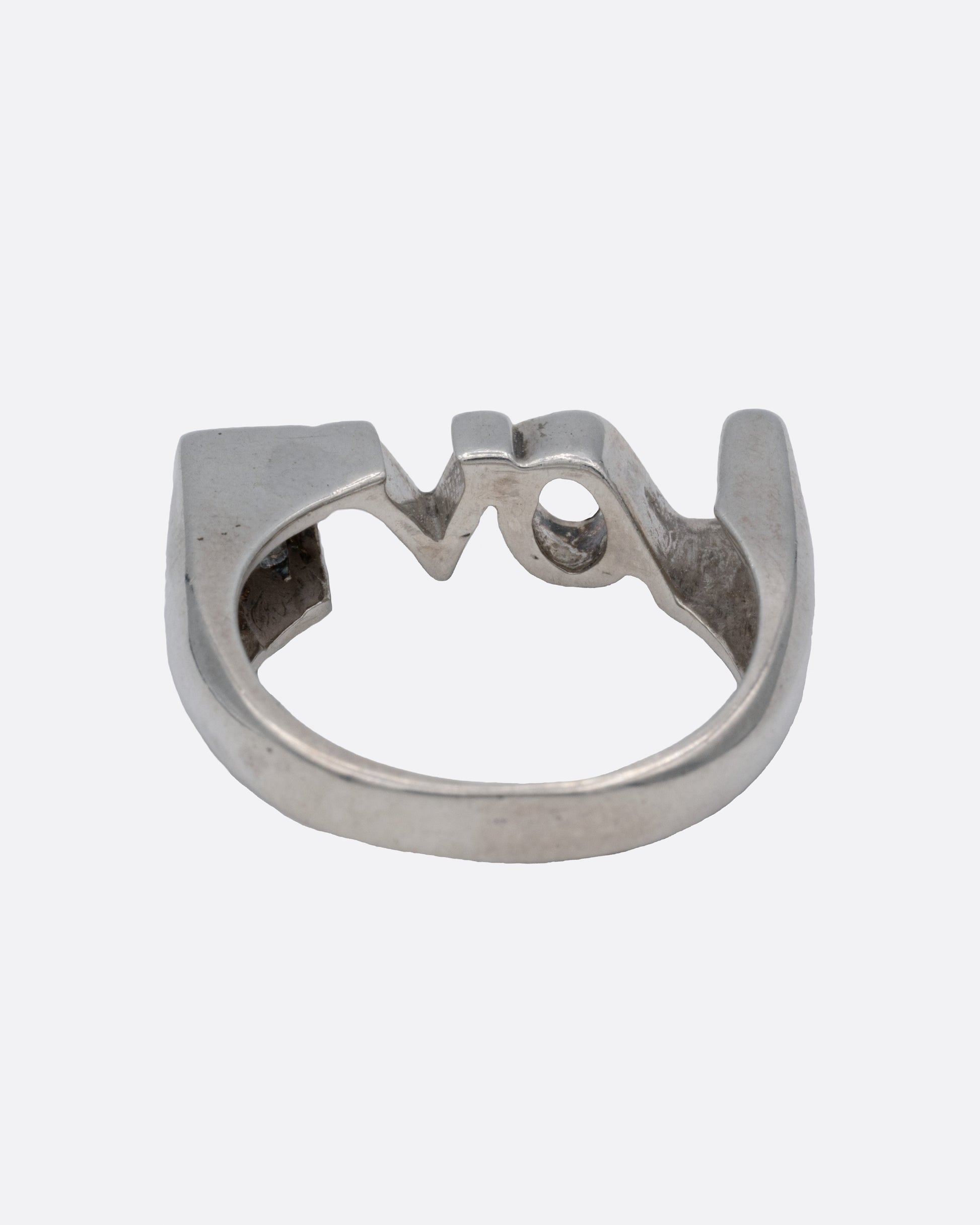 A silver ring with the letters LOVE, shown from the back.