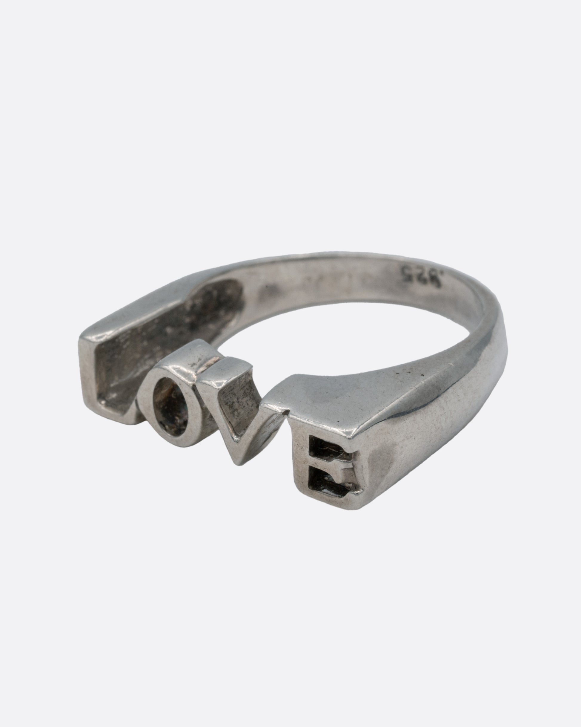 A silver ring with the letters LOVE, shown from the side.