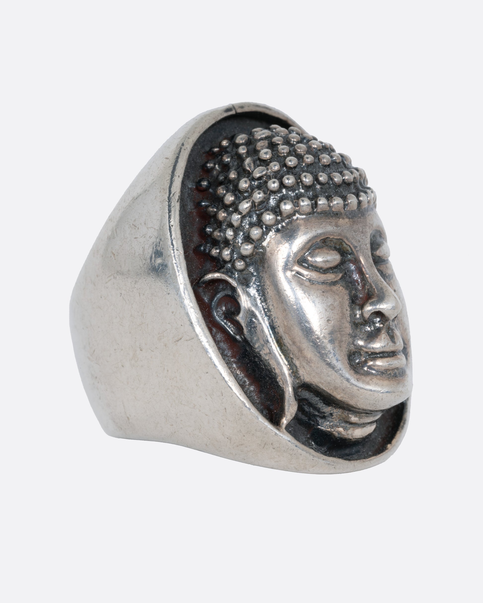 A silver ring with the Buddha's face. Shown from the side.