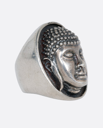 A silver ring with the Buddha's face. Shown from the side.