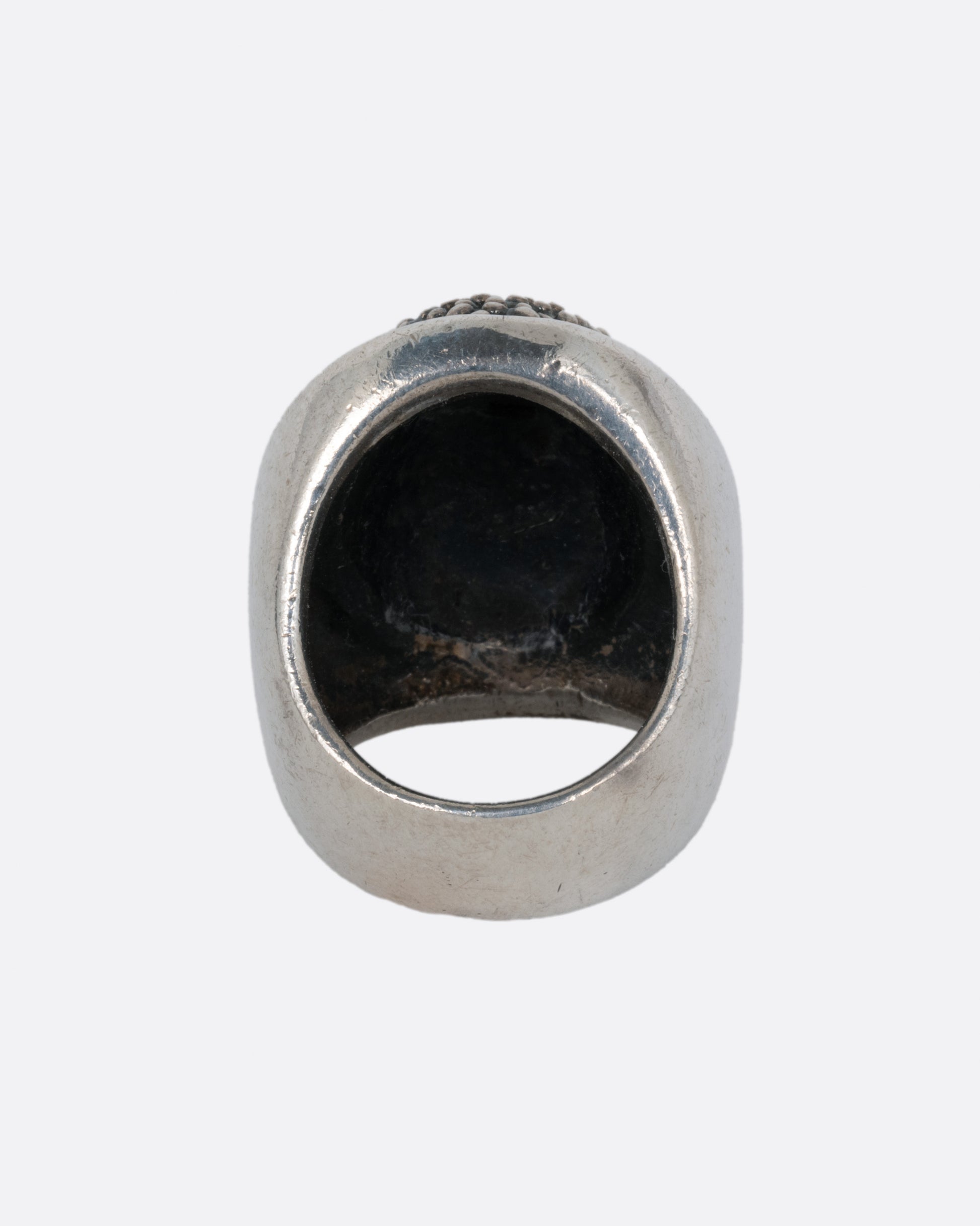 A silver ring with the Buddha's face. Shown from the back.