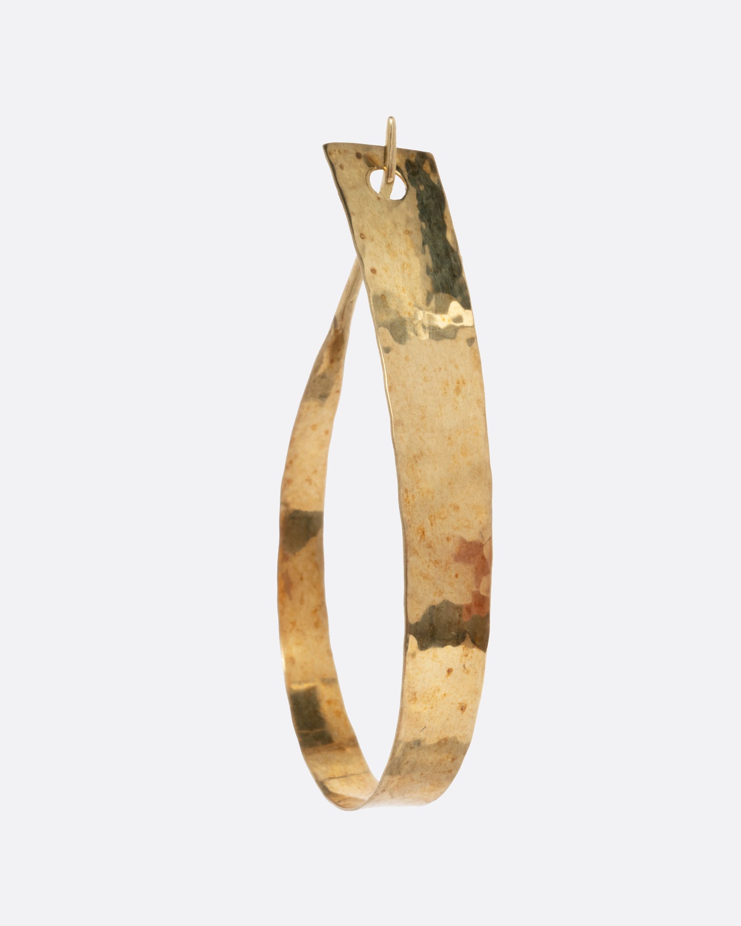 A yellow gold loop earring with a tapered silhouette and minimalist closure, shown from the side.