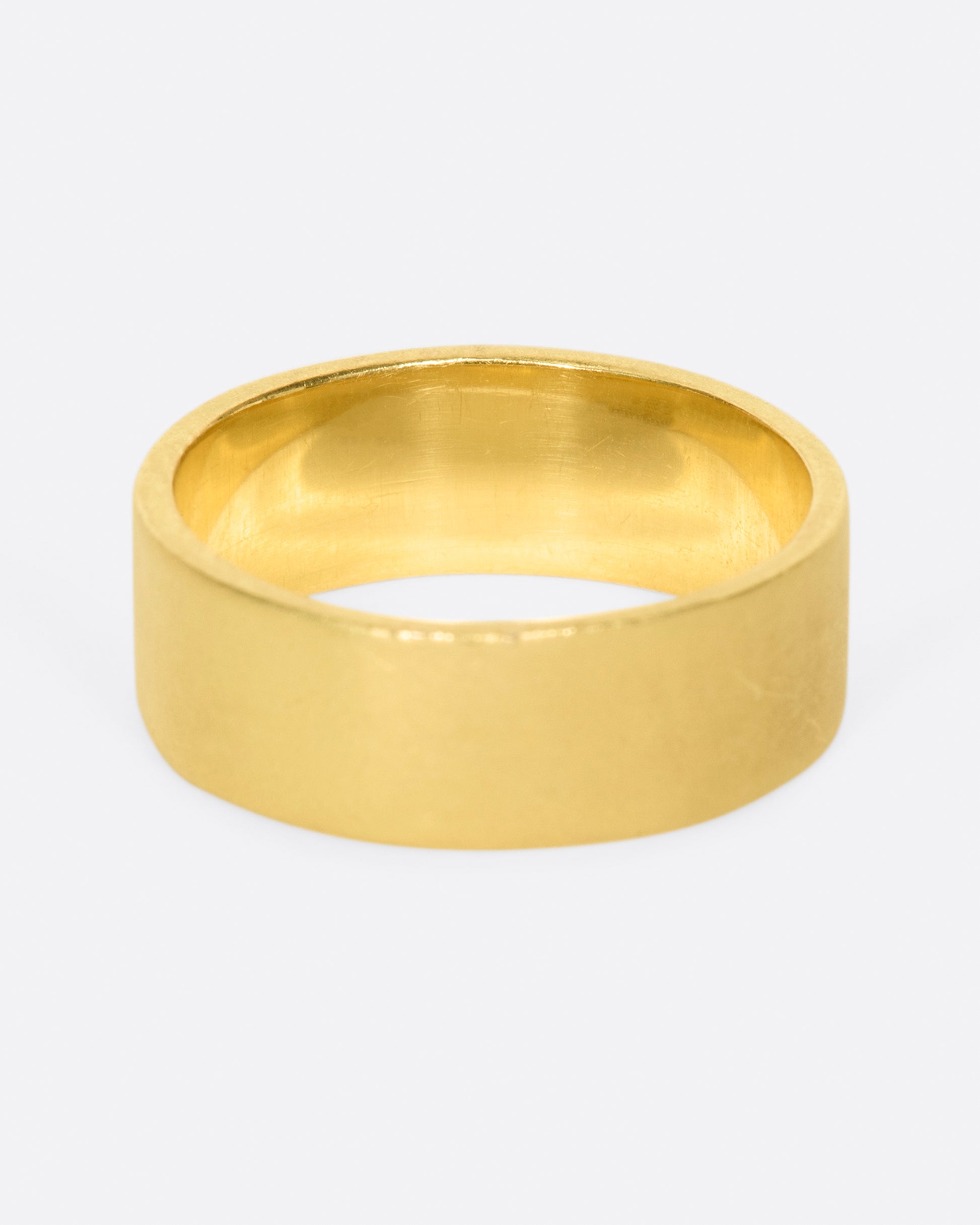 A yellow gold band with 15 grey diamonds in three rows of five at the center. Shown from the back.