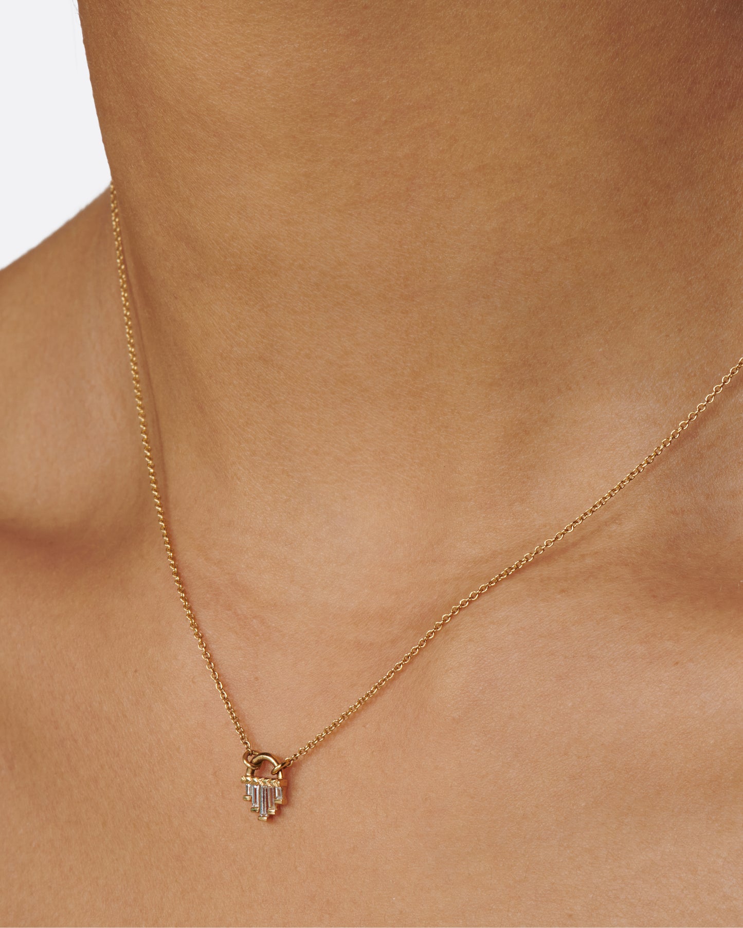 A curved gold pendant necklace with five diamond baguettes.