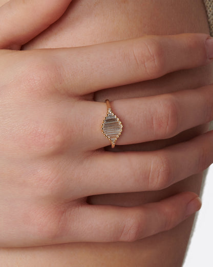 A signet ring with a face made entirely of baguette diamonds. Shown on a hand.