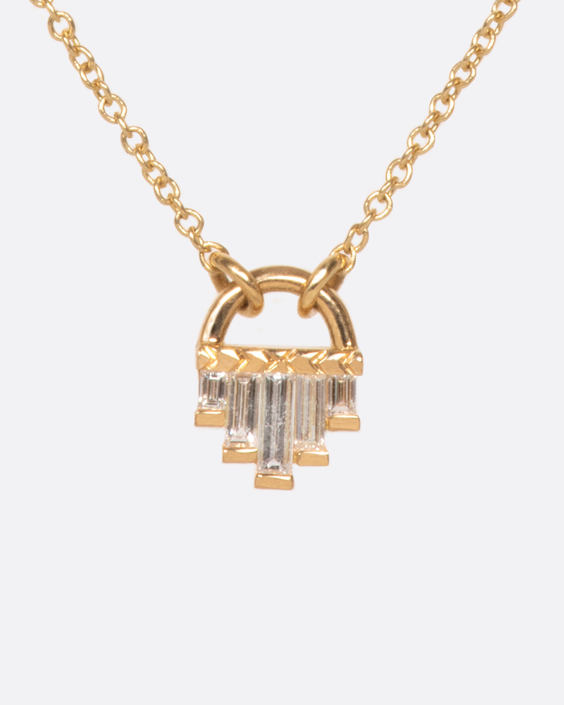 A curved gold pendant necklace with five diamond baguettes.