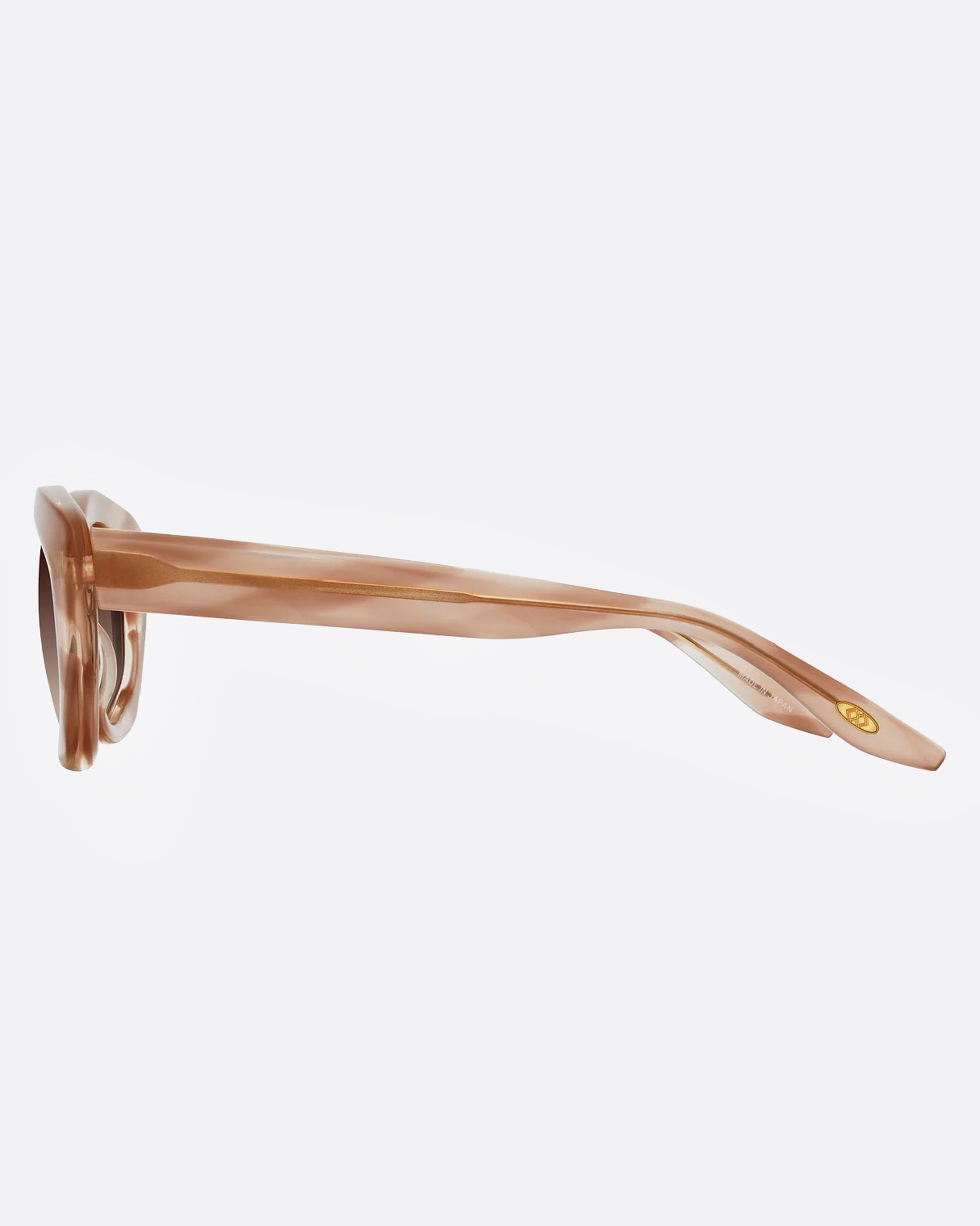 A pair of sunglasses with a cat-eye silhouette and dusty rose marbled frames and brown gradient lenses, shown from the side.