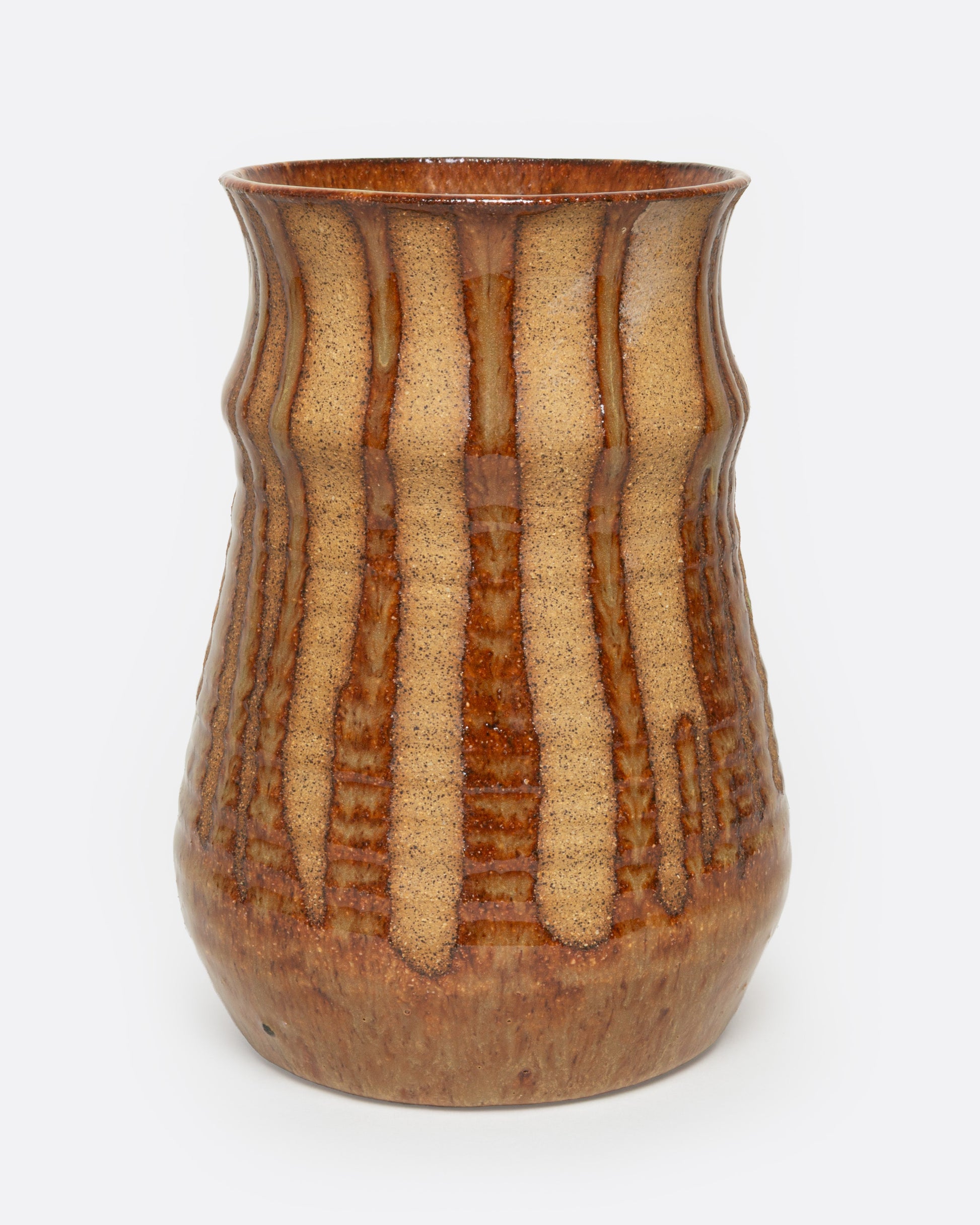 A tan ceramic vase with a dripped umber glaze, shown from the front.