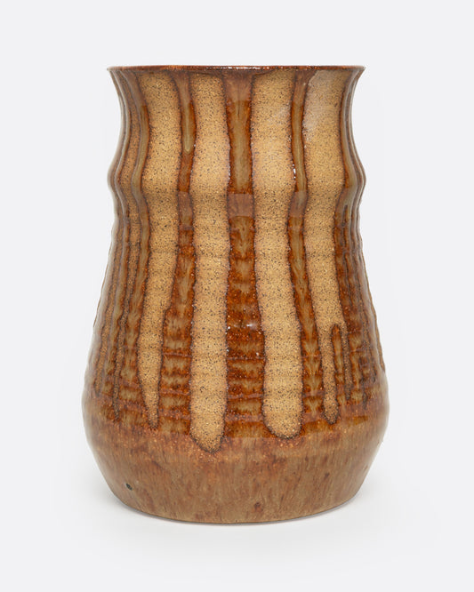 A tan ceramic vase with a dripped umber glaze, shown from the front.