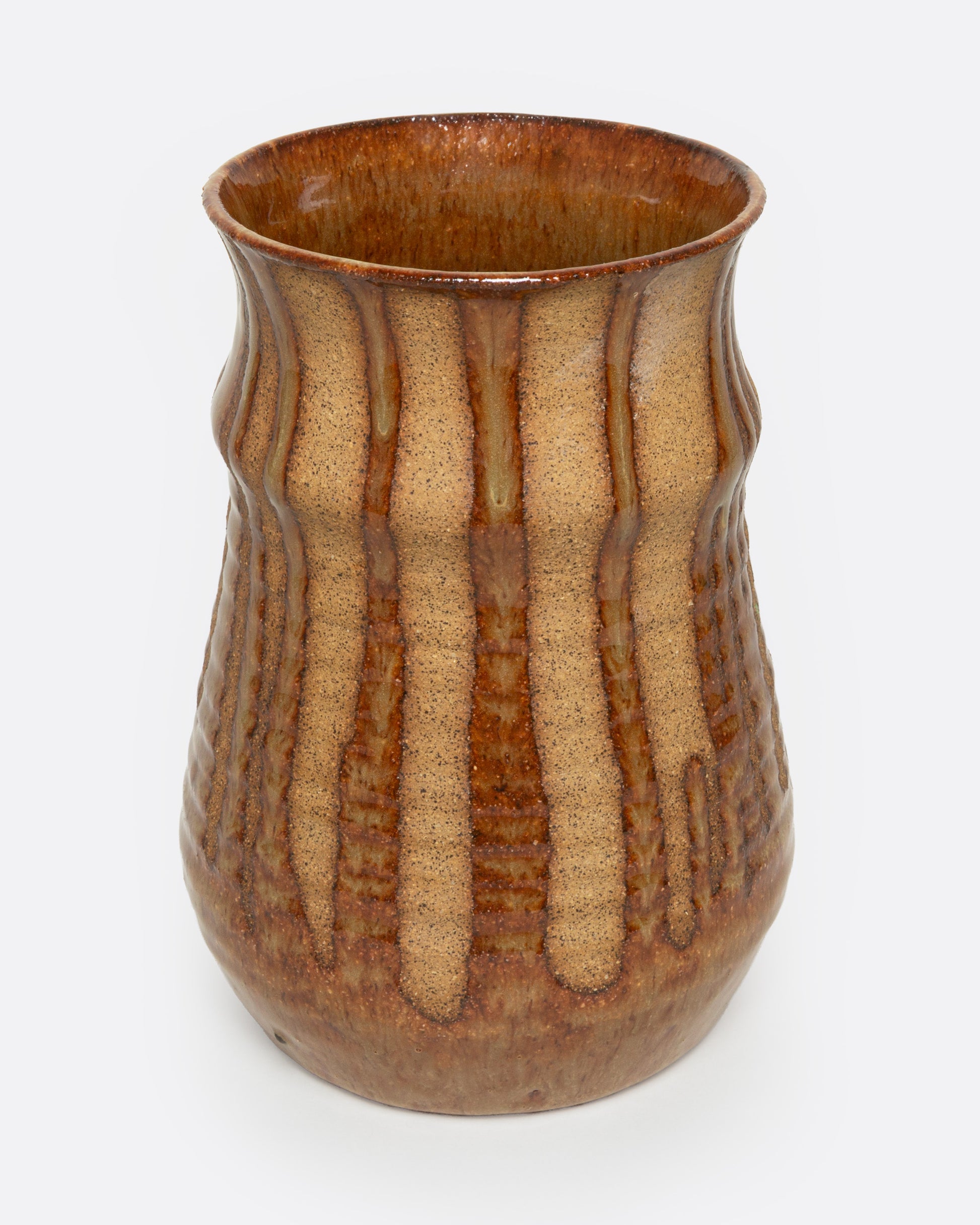 A tan ceramic vase with a dripped umber glaze, shown from the front.