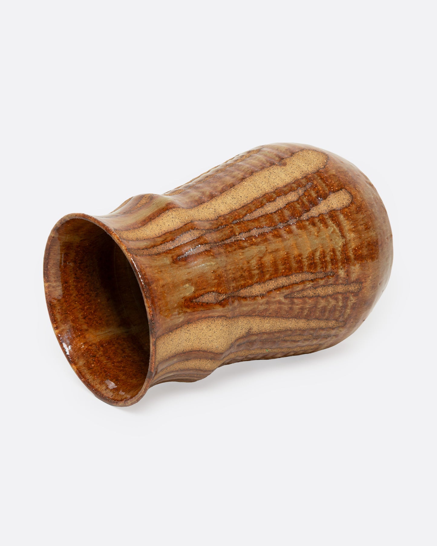 A tan ceramic vase with a dripped umber glaze, shown from the side.