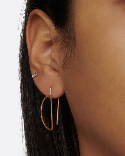 Gold wire geometric hook earrings worn on an ear