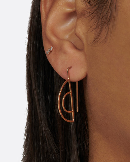 Gold wire half circle hook earrings worn on an ear