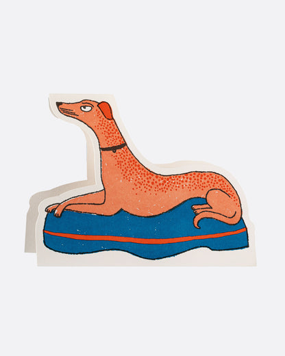 Archivist Gallery crossed paw dog die-cut card, an orange dog lying on a blue cushion with its paws crossed