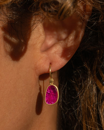 Lola Brooks earring in 18k yellow gold worn on an ear, a faceted Mozambique ruby pebble in a gold bezel on a hook wire