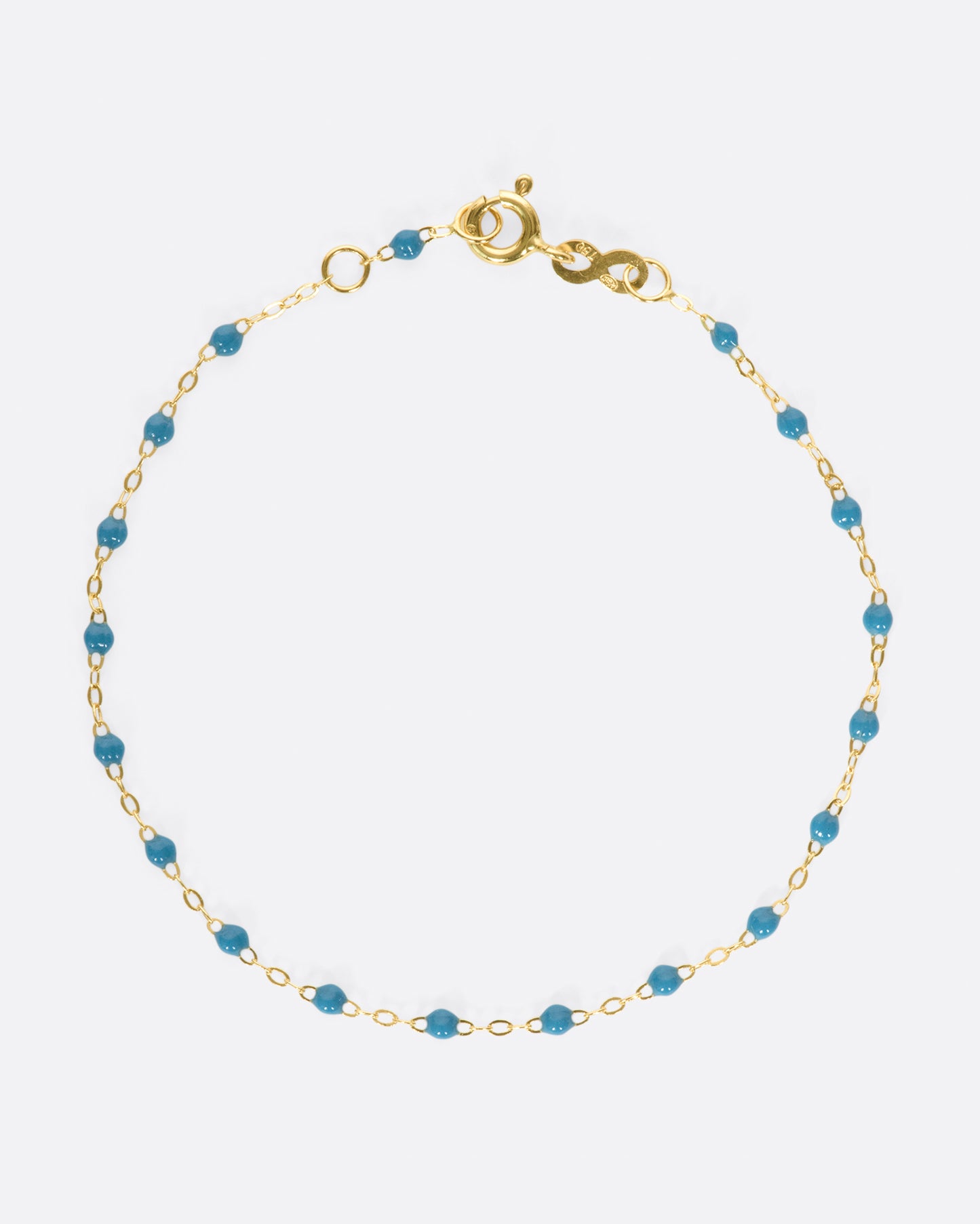 A yellow gold cable chain bracelet with droplets of blue resin. Shown closed from the top.