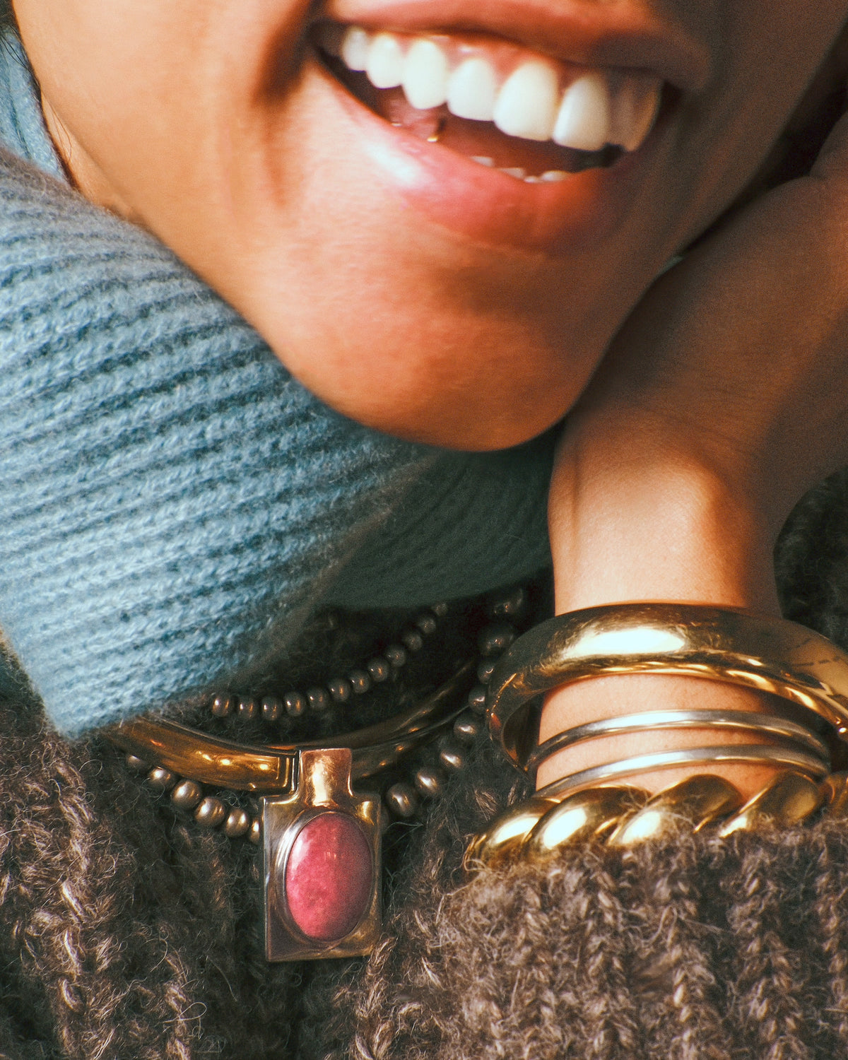A sterling silver rectangular pendant with an oval pink stone cabochon shown styled around a neck paired with a gold collar and beaded silver necklace.