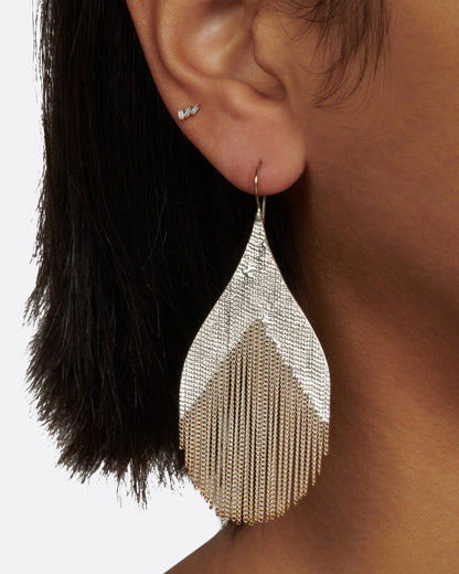 Silver strand teardrop earrings worn on an ear