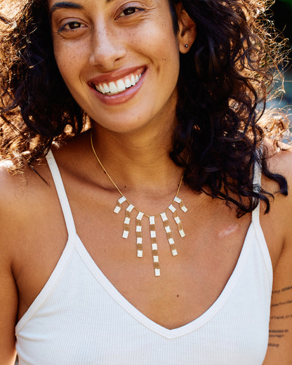 A yellow gold cable chain necklace with seven clusters of cable chain fringe with alternating bits of silver solder. Shown from the front on a woman.