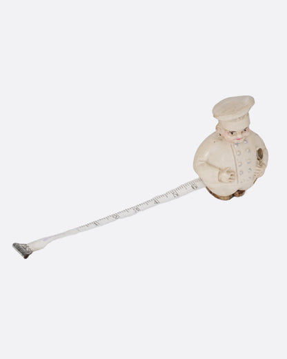 A chef shaped tape measurer, shown from the top with the tape pulled out.
