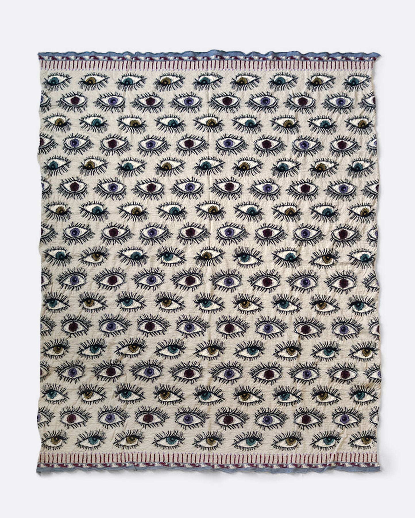 A cream colored compressed wool blanket from with an all- over eye pattern. Shown open lying flat.