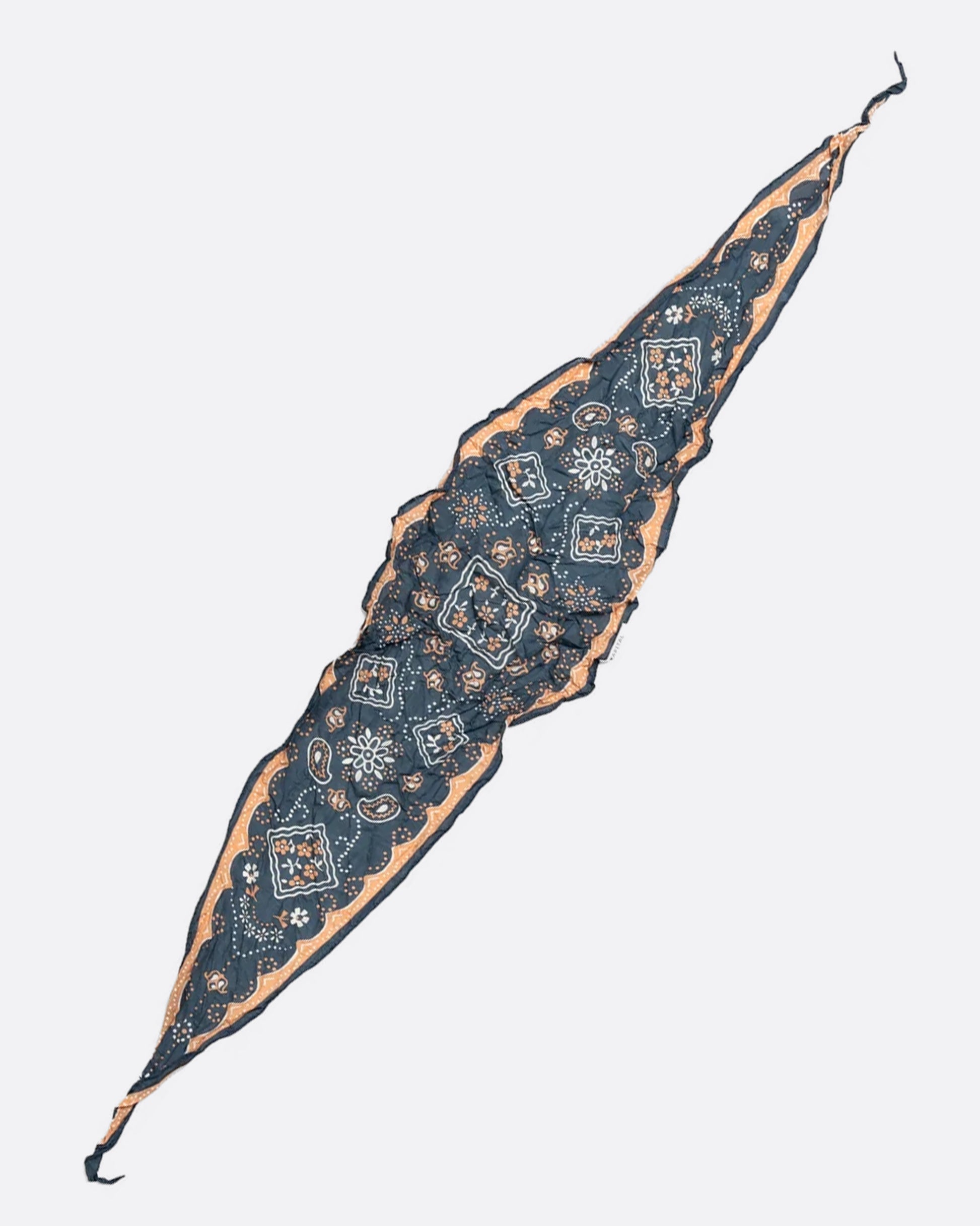 A navy colored diamond-shaped neckerchief with a paisley motif. Shown lying flat. 