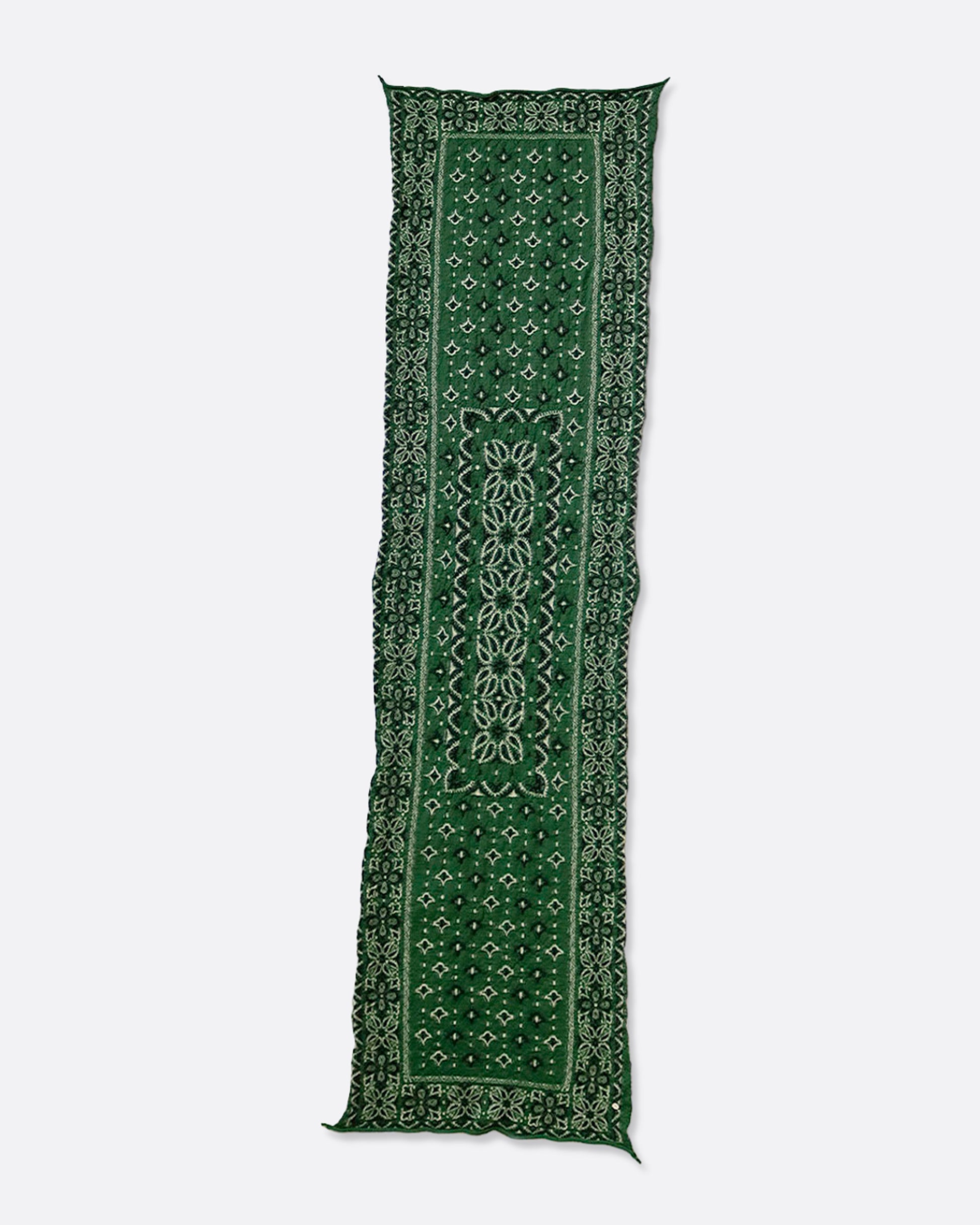 A green compressed wool scarf with a classic bandana pattern, shown lying flat.
